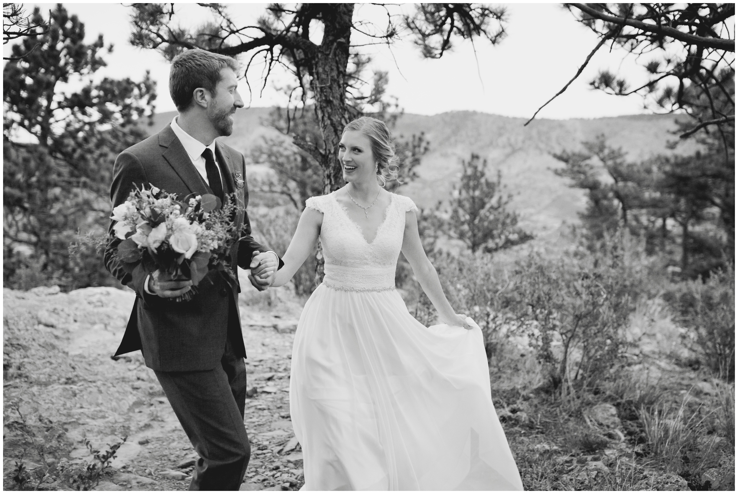 black and white candid wedding photo of couple walking through forest at Lionscrest Manor Colorado wedding 