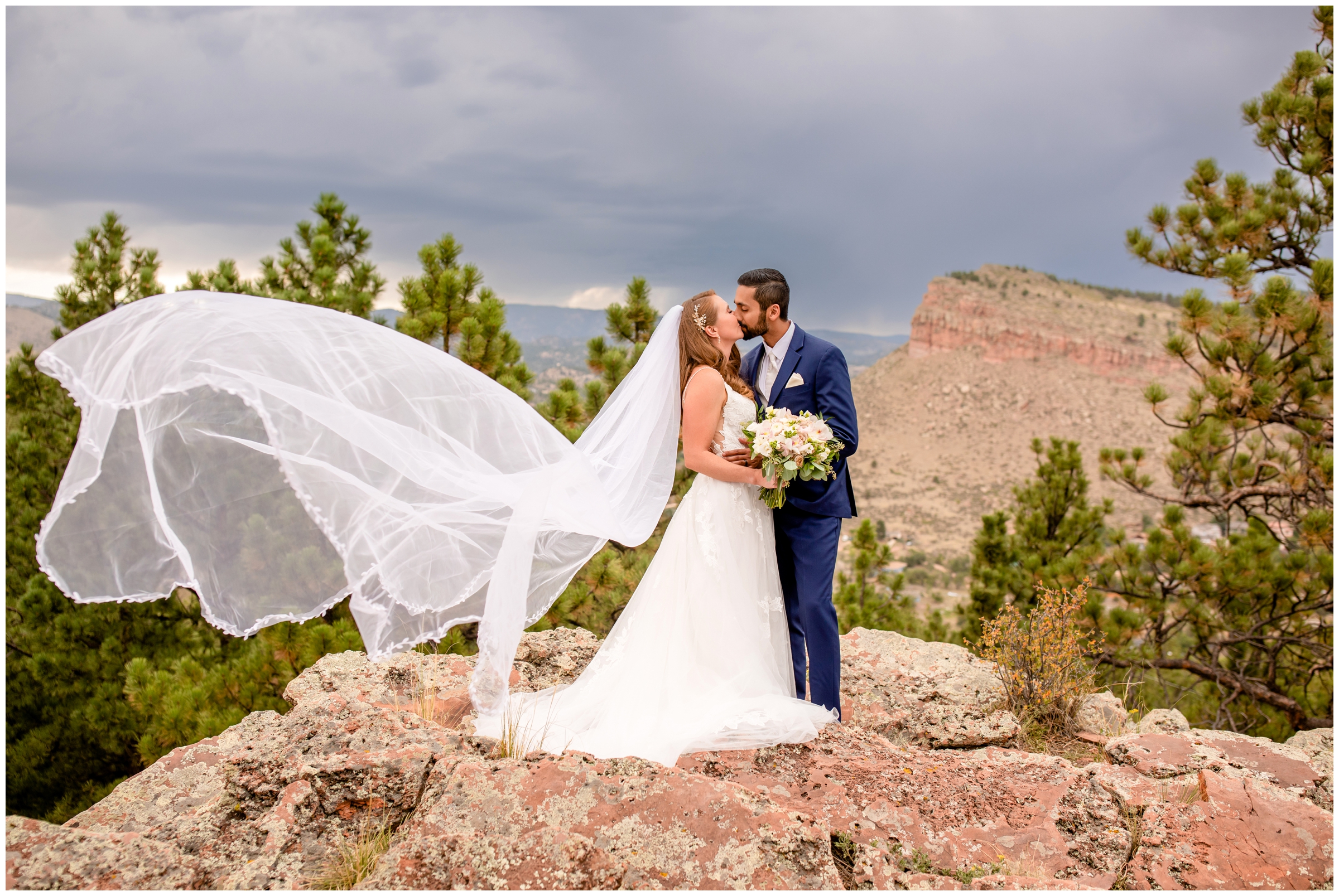 couple kissing with veil blowing in the wind during Lyons Colorado mountain wedding pictures at Lionscrest Manor