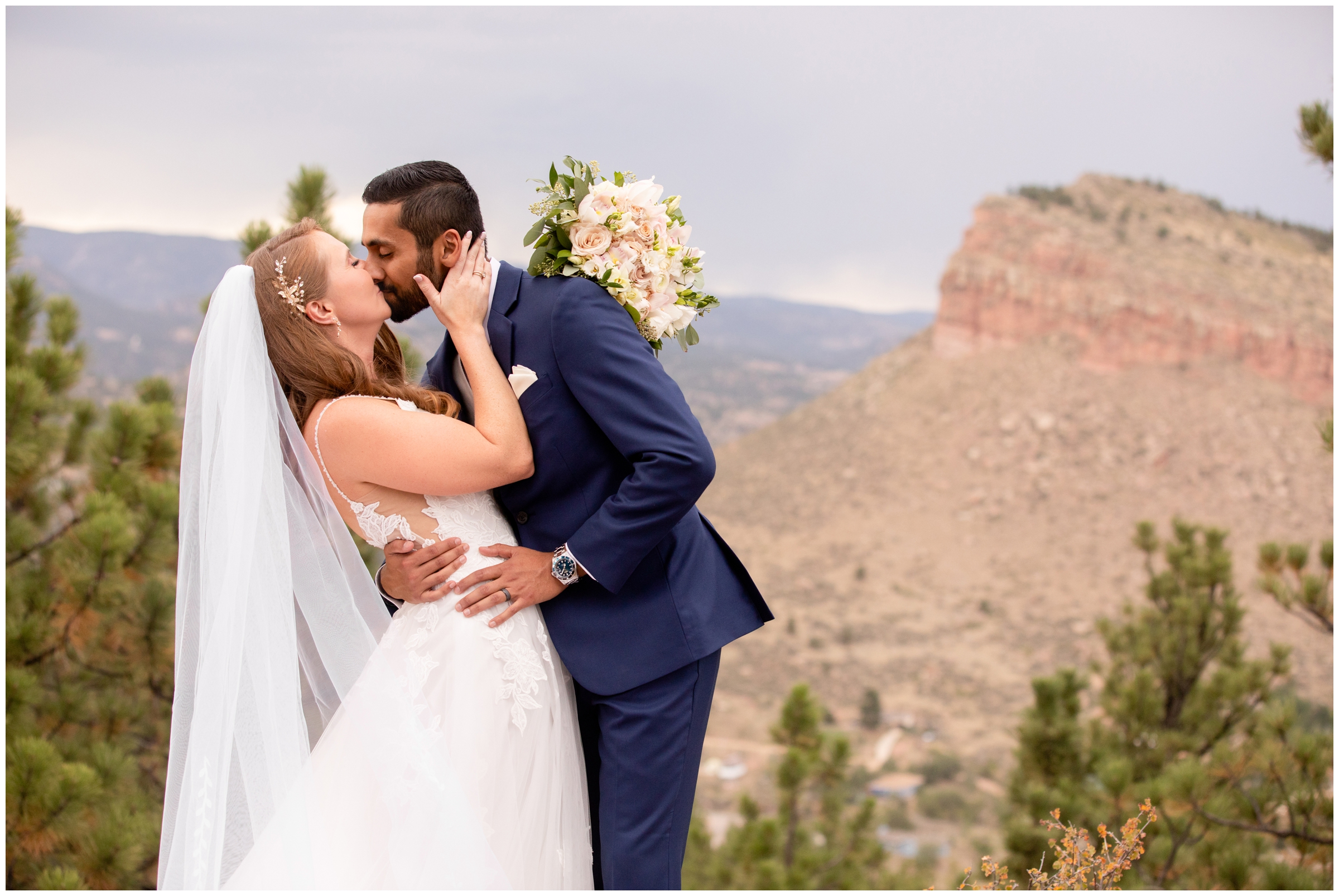 couple kissing with mountains in background at Colorado summer wedding at Lionscrest Manor
