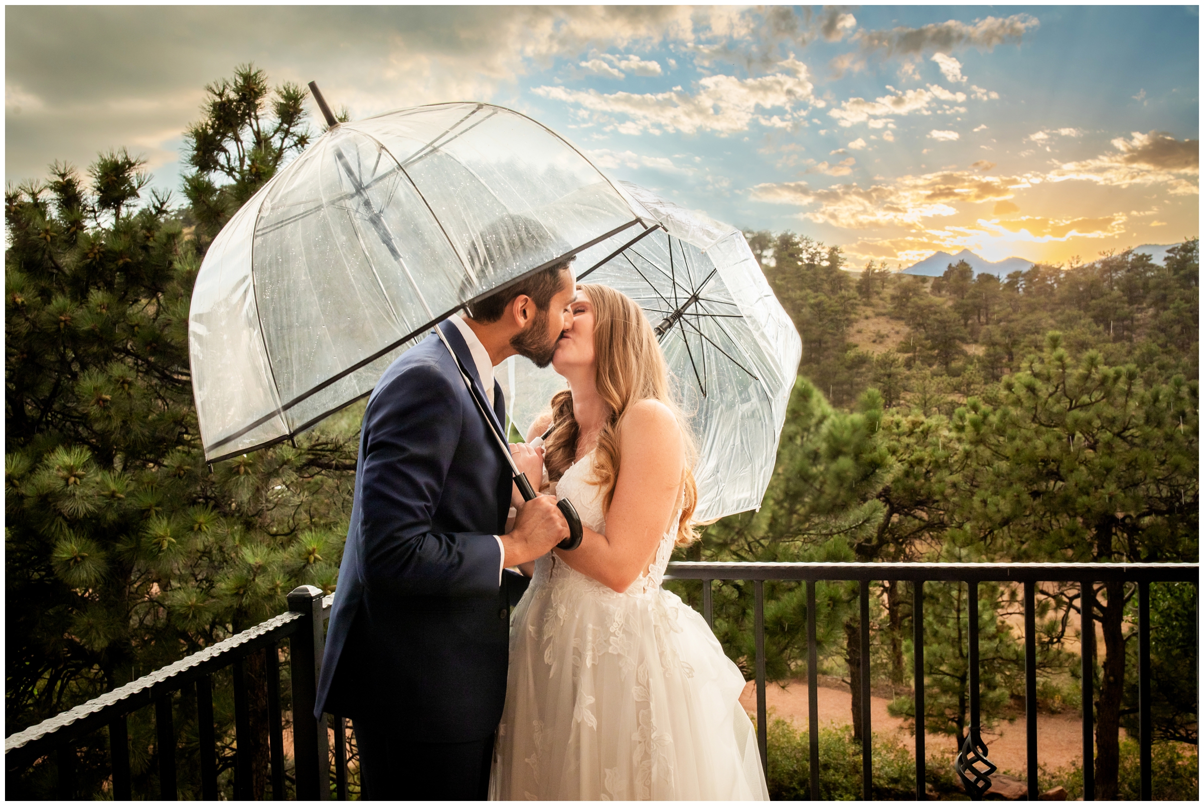 couple kissing under umbrellas at rainy Colorado mountain wedding at Lionscrest Manor