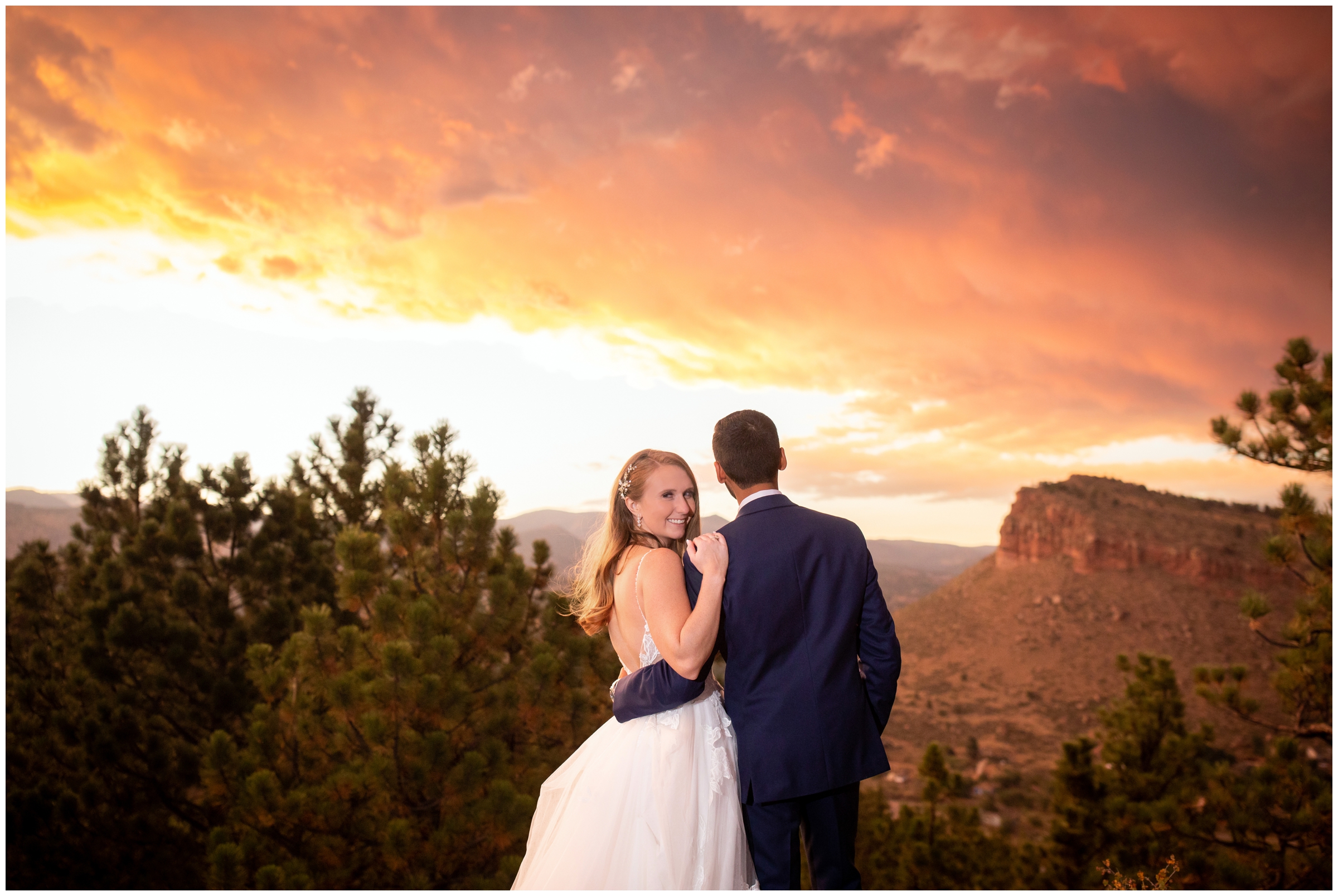 couple posing on edge of mountain under colorful sunset during Lionscrest Manor Colorado wedding pictures