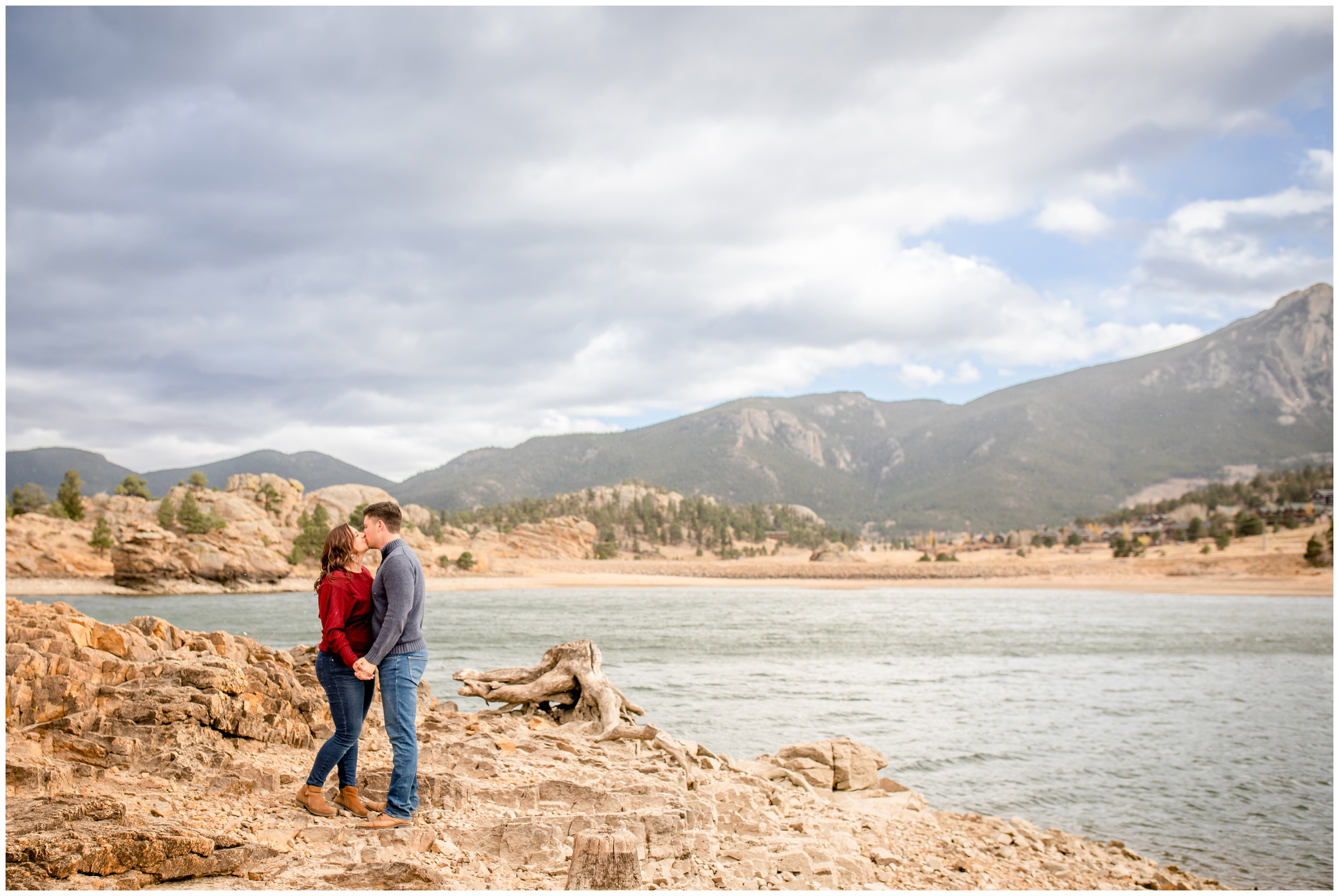 couple kissing next to mountain lake during portrait session in Estes Park Colorado
