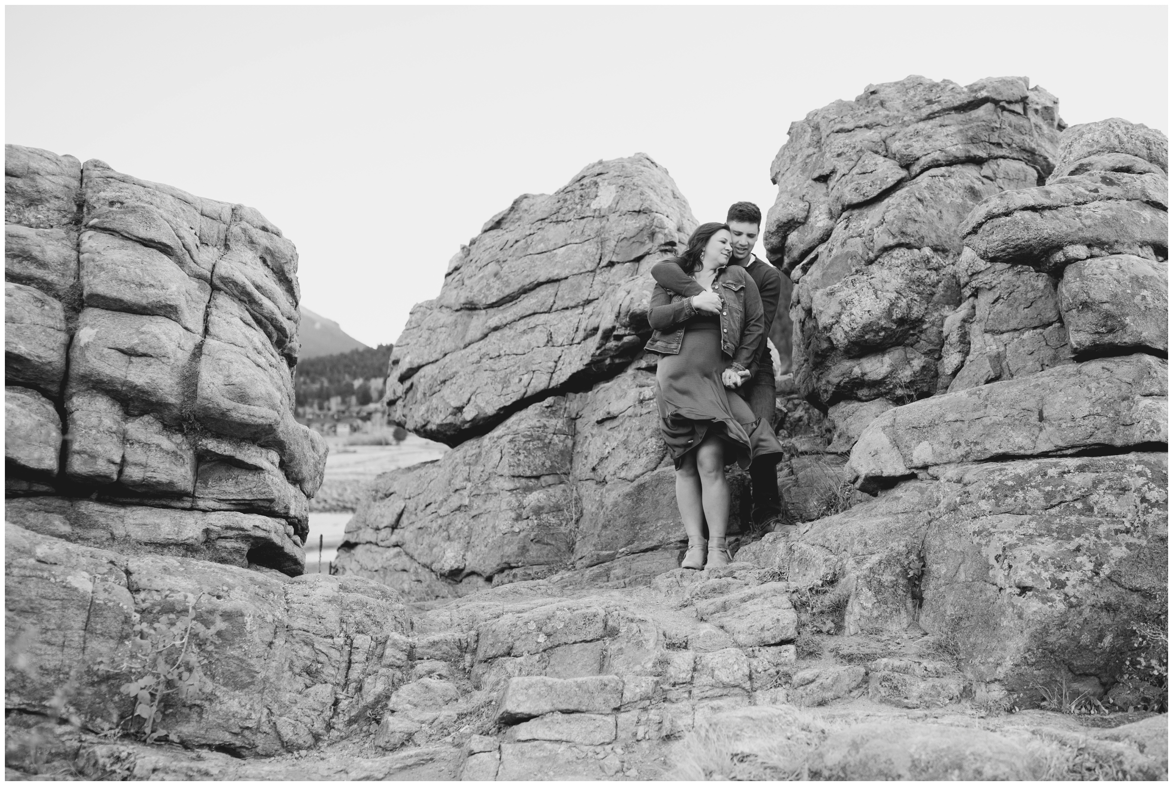 couple posing on rock formations during windy Colorado couples photo shoot in Estes Park 