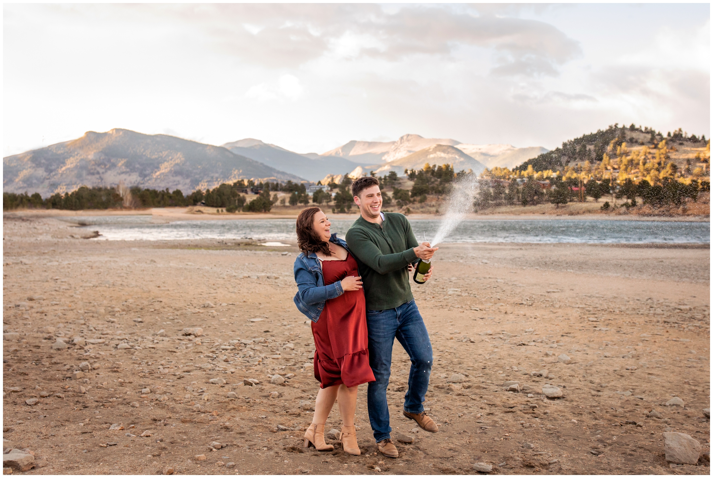 couple popping champagne during Colorado mountain lake engagement photography session 