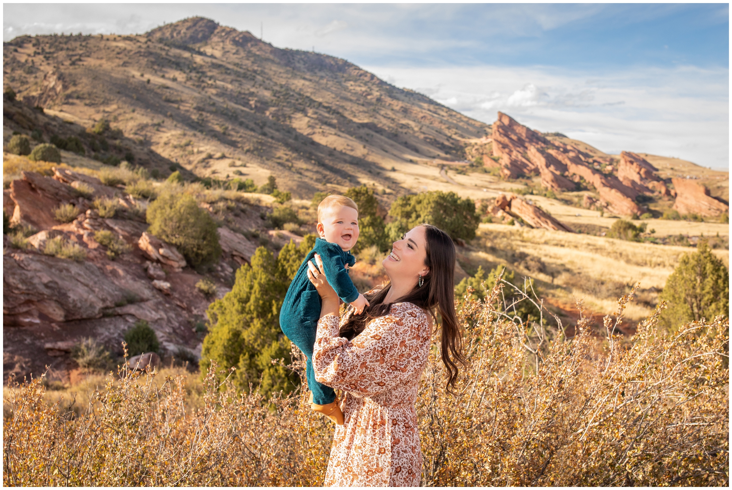 mom lifting son with red rocks in background at Mount Falcon East Colorado 