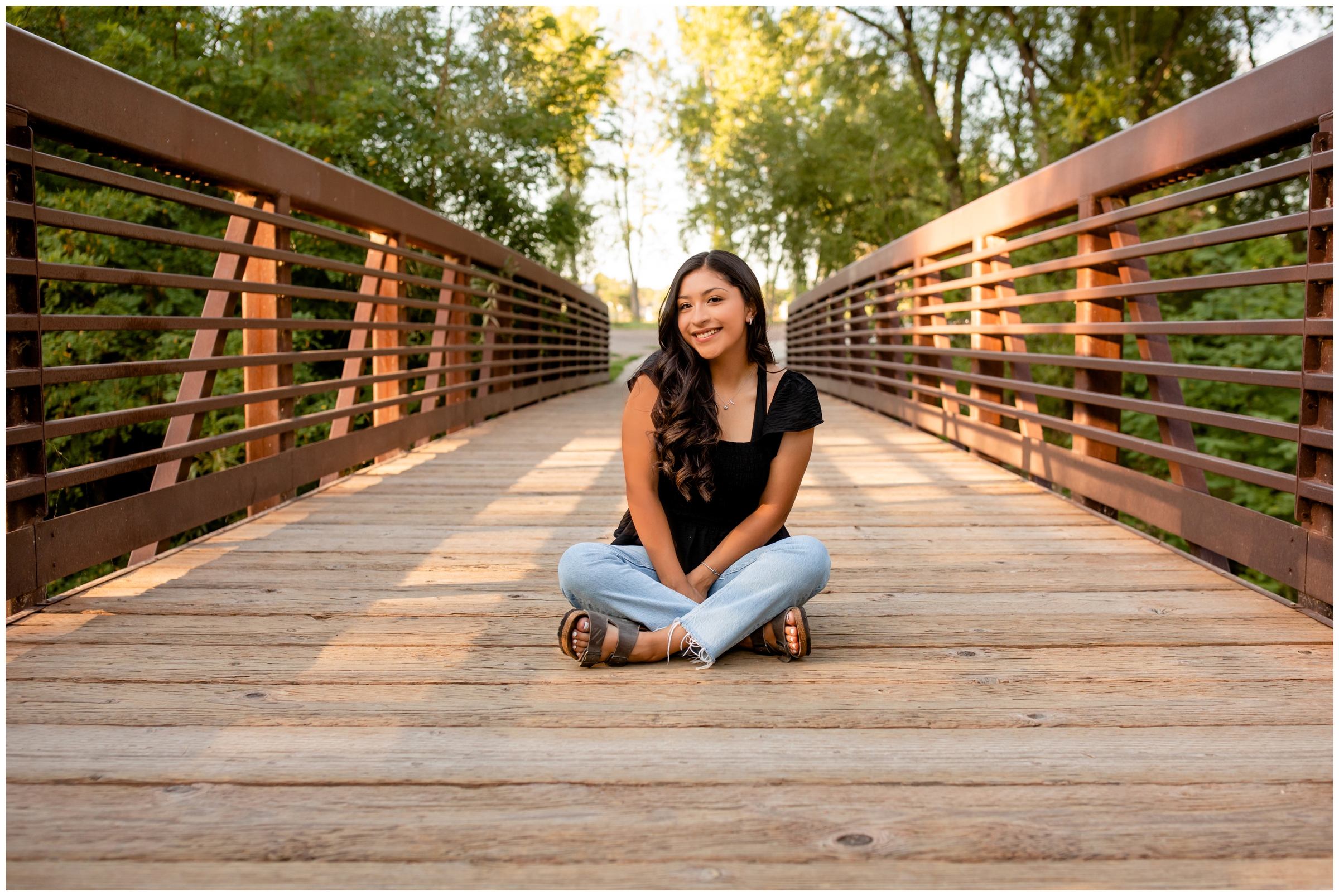 teen sitting on wooden bridge during senior portraits in Longmont Colorado