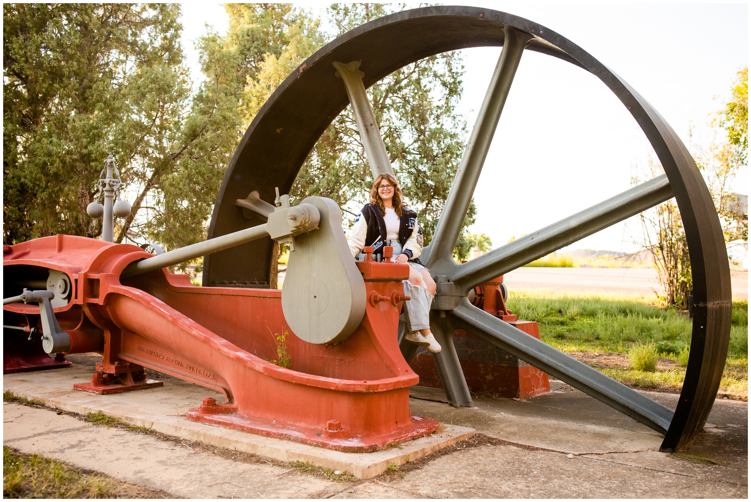 teen girl sitting on old compound steam engine during unique Colorado senior pictures in Boulder 