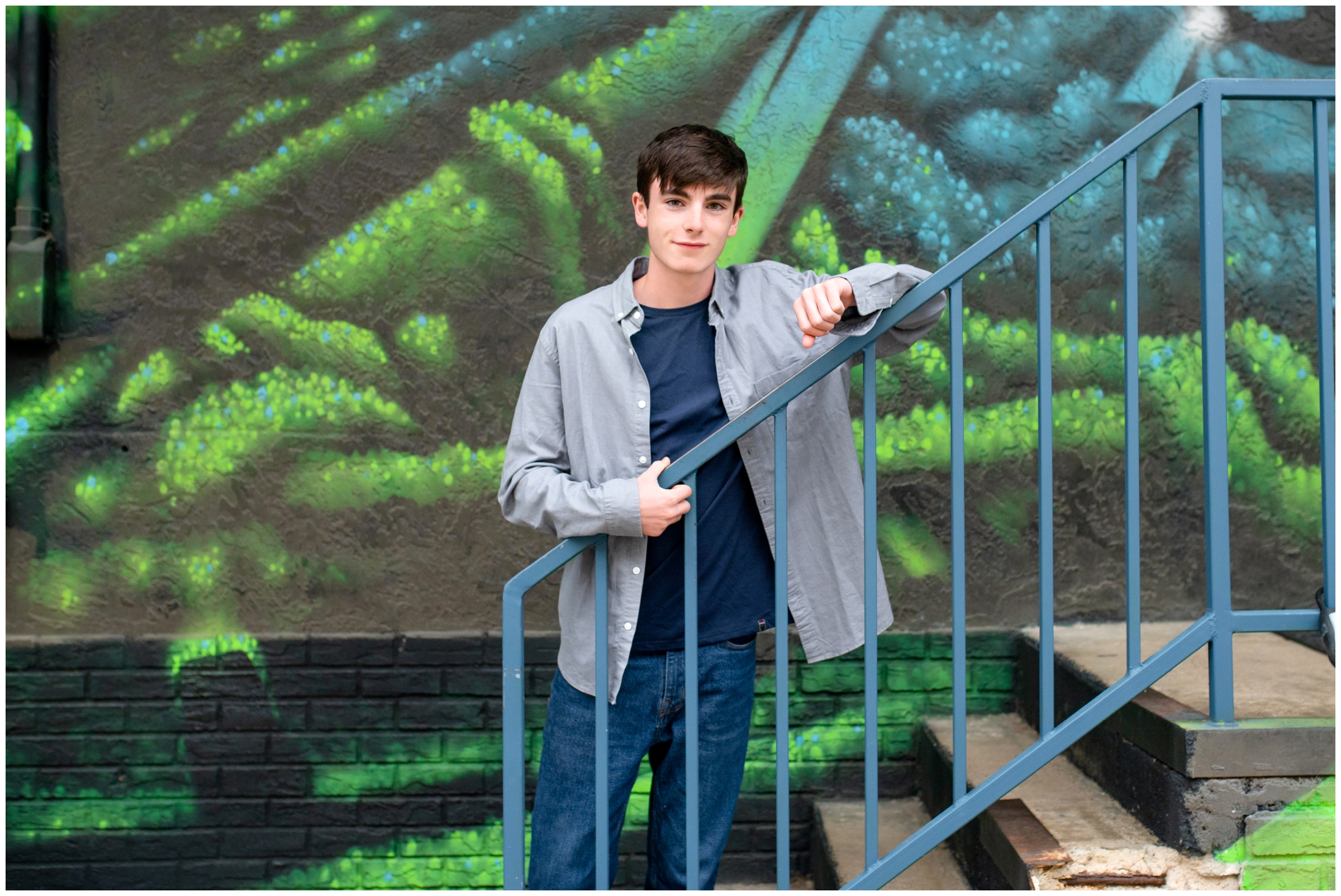 teen guy posing in front of colorful wall mural during urban Colorado senior pictures 