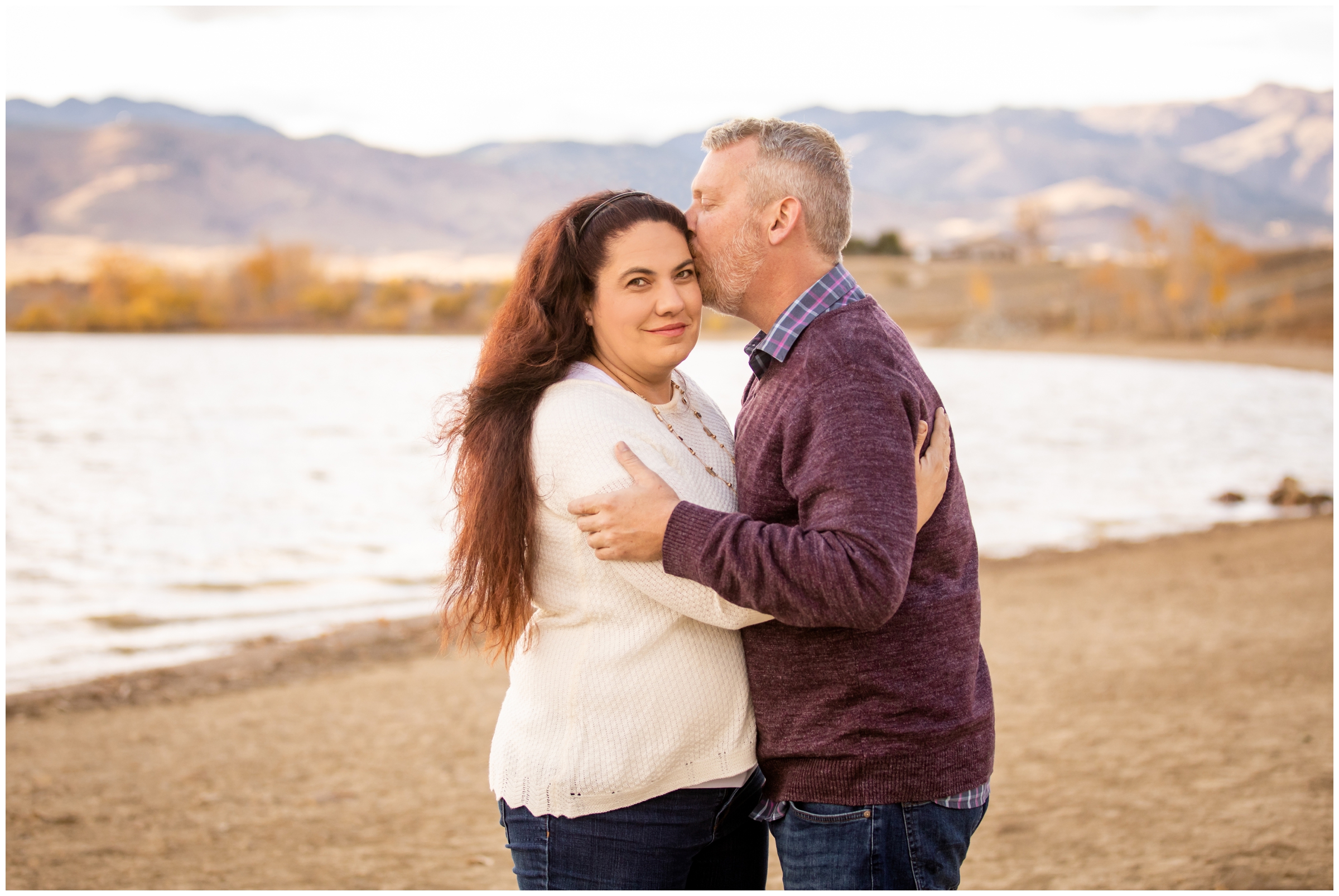 couple kissing in front of mountain lake during Boulder Colorado engagement portraits 