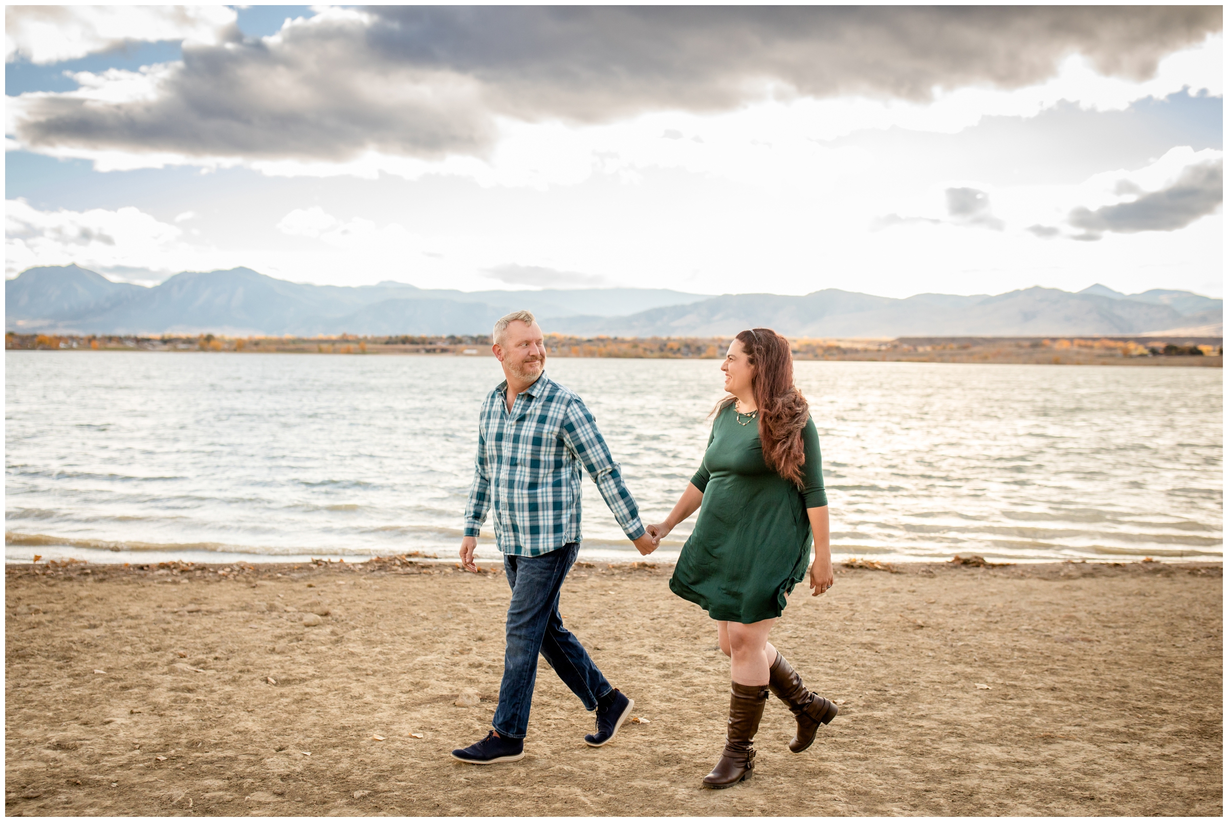 couple walking in front of mountain lake during candid engagement photography in Boulder Colorado