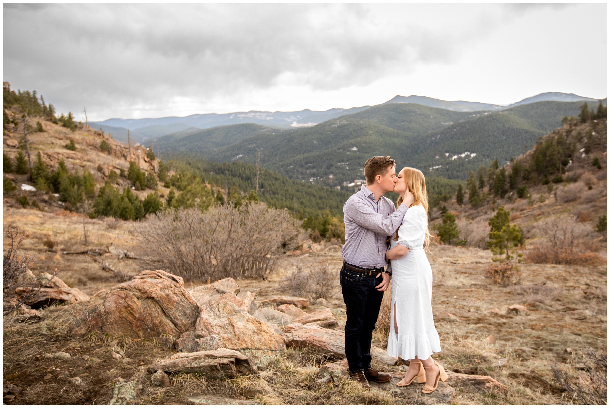 couple kissing with mountains in background at Mount Falcon West CO