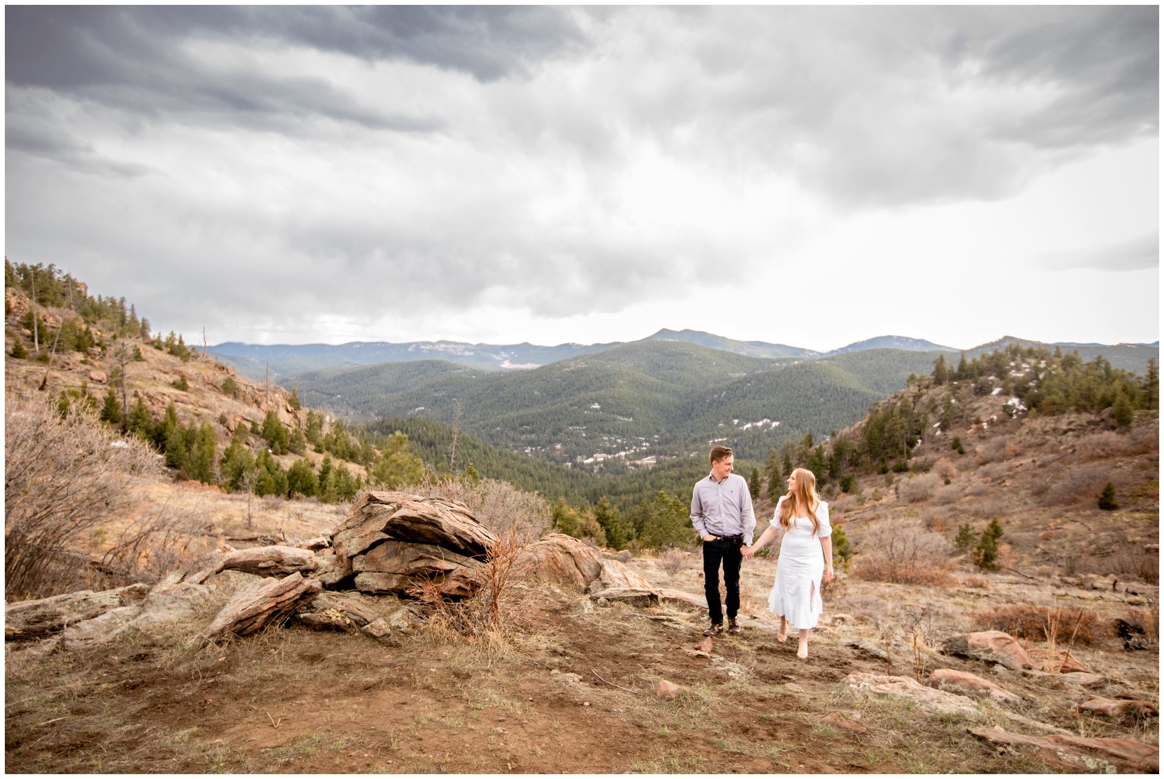 couple holding hands and walking with mountains in background during Colorado couples photography session 