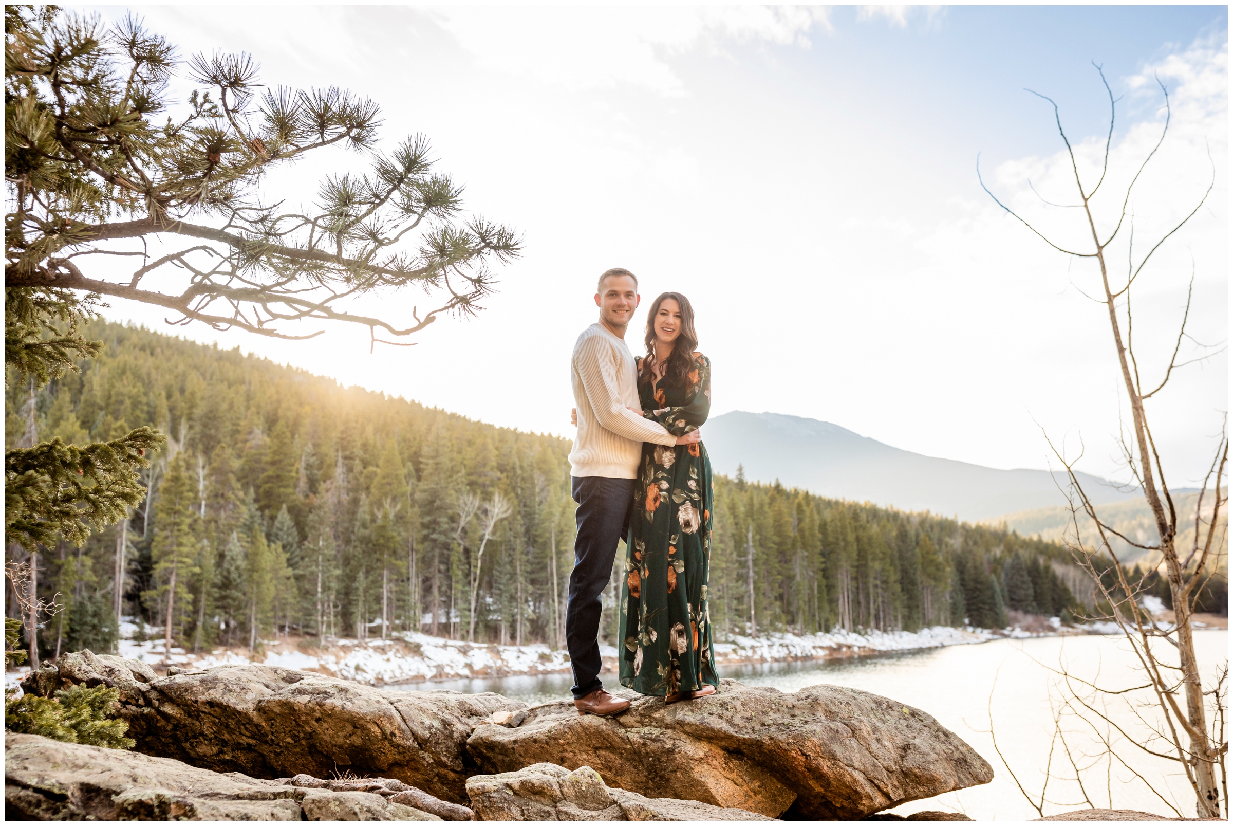couple posing on rock formations with mountains in background during Evergreen engagement portraits 