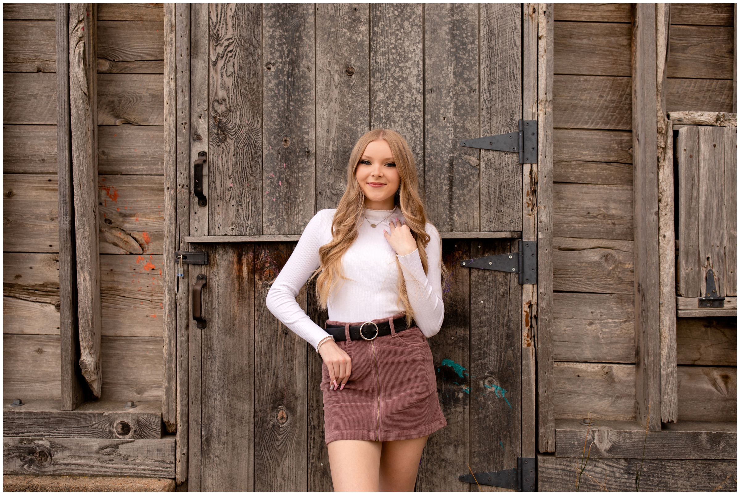 teen leaning against wooden barn during Longmont Colorado fall senior pictures at Sandstone Ranch