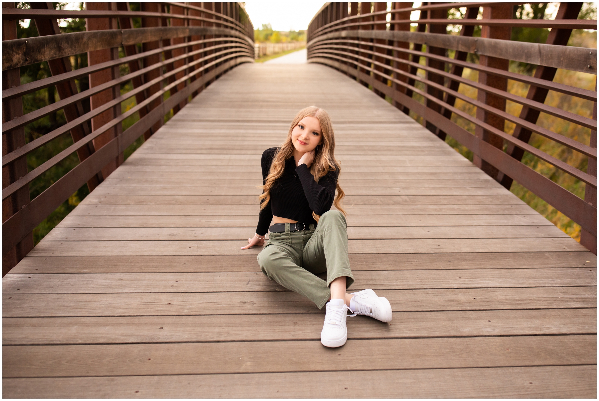 teen sitting on wooden bridge during Longmont Colorado senior pictures during fall