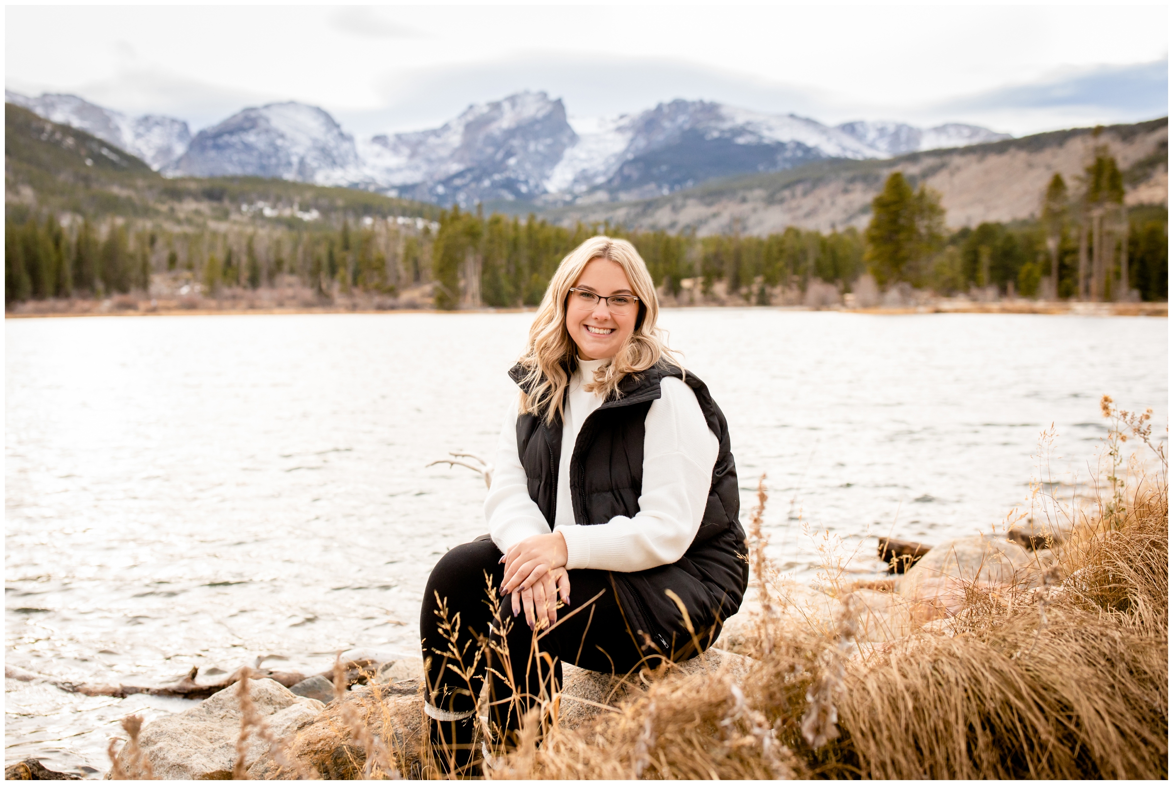 teen sitting on rock with mountains and lake in background during Colorado mountain senior pictures in RMNP
