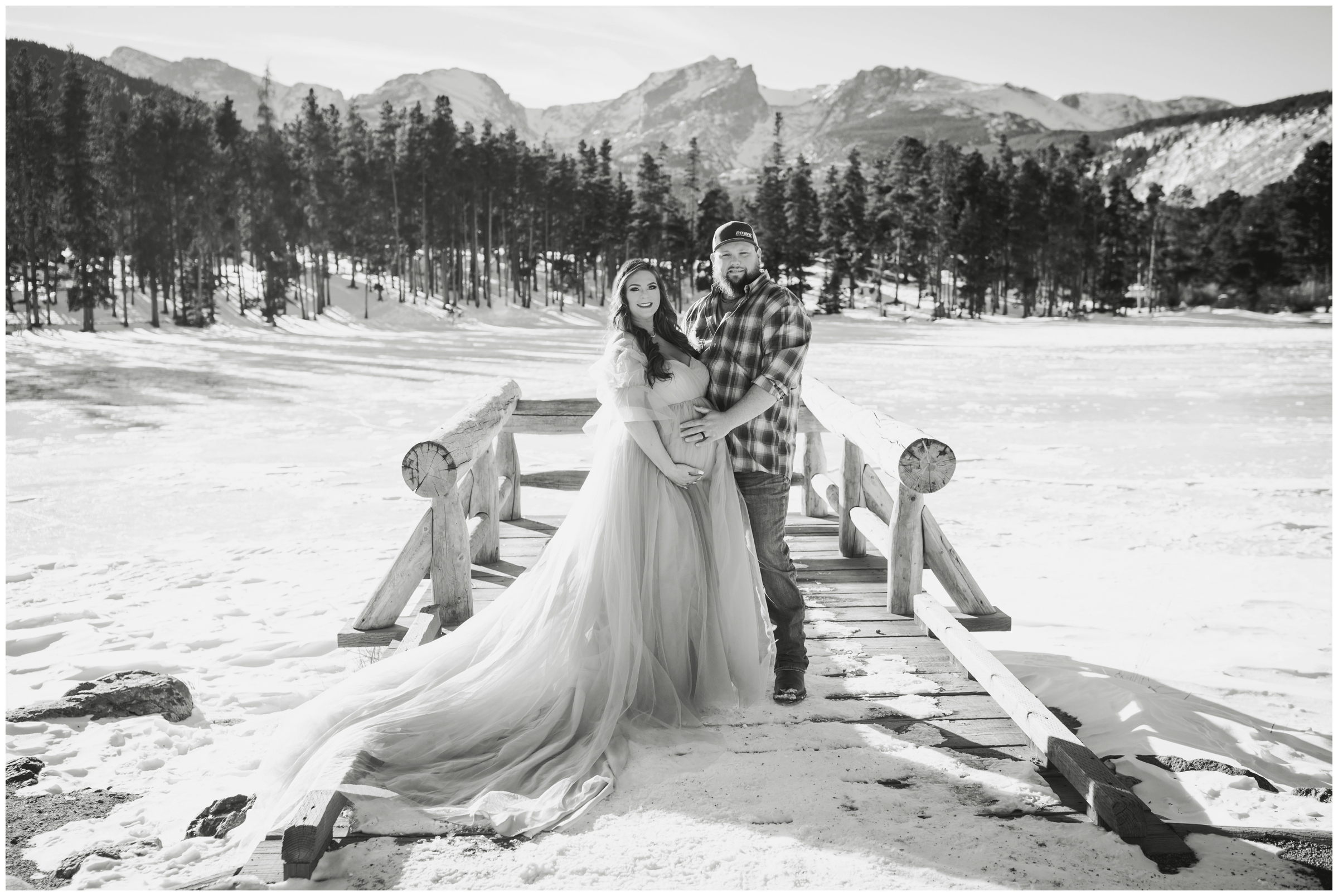 couple posing on dock at Sprague Lake during Colorado winter maternity pictures in Estes Park 