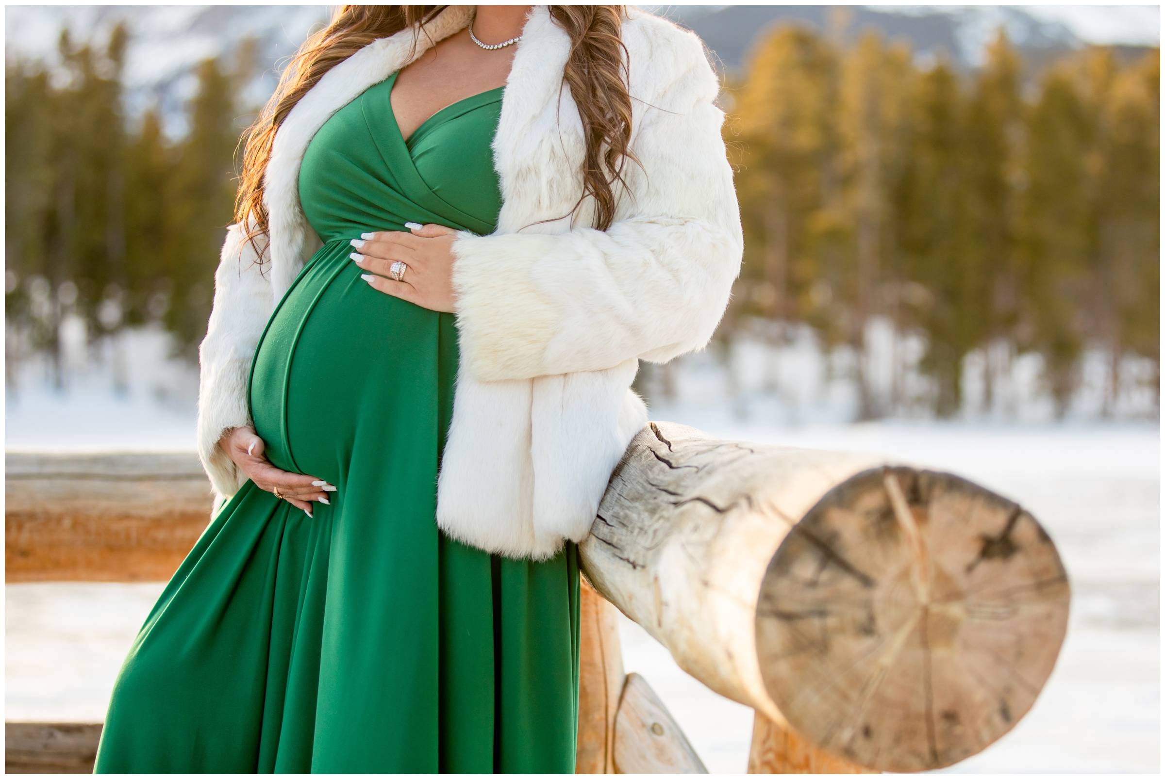 pregnant woman posing on dock at Sprague Lake during winter portrait session in Estes Park 
