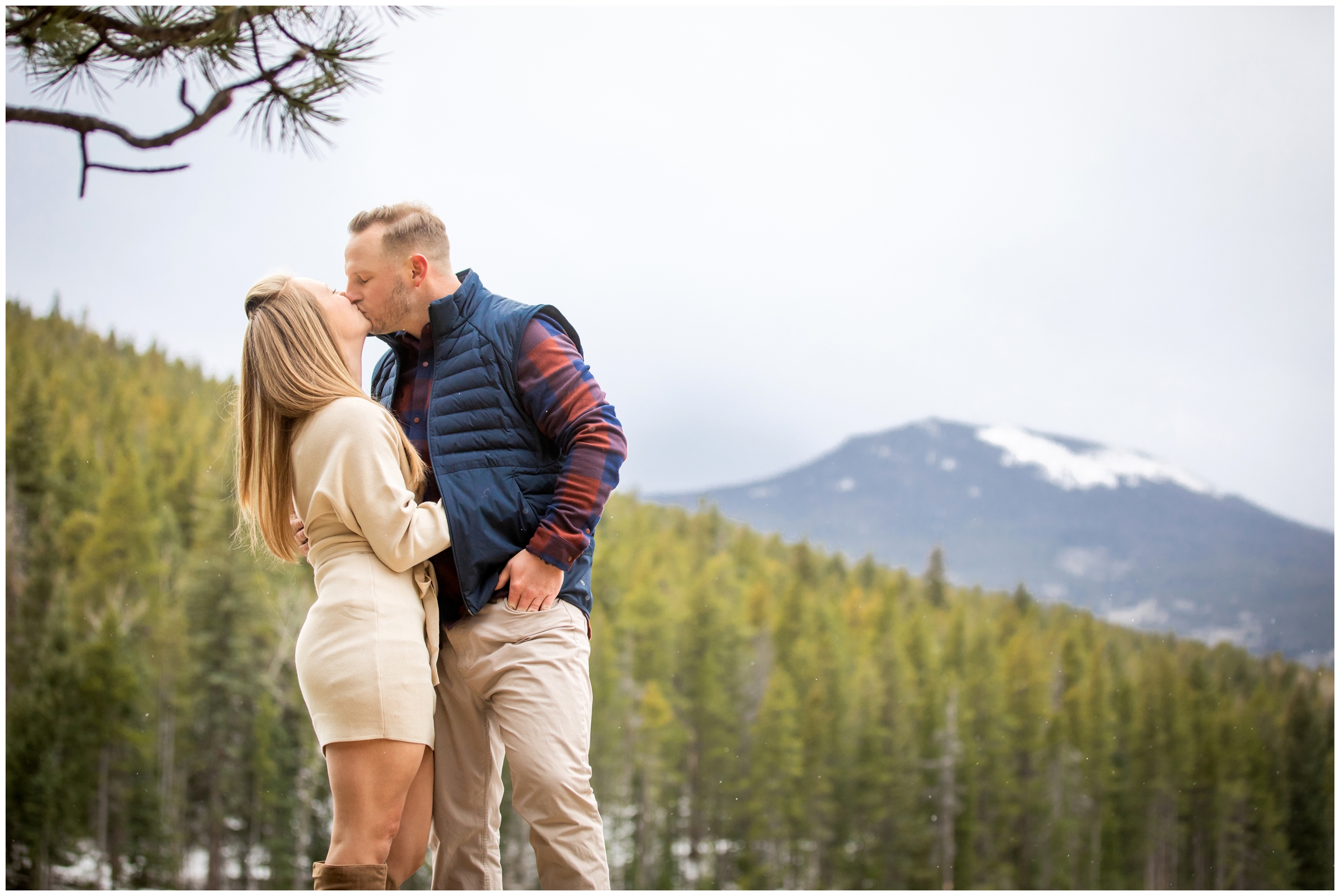 couple kissing with mountains in background during fall couples portraits in Evergreen 