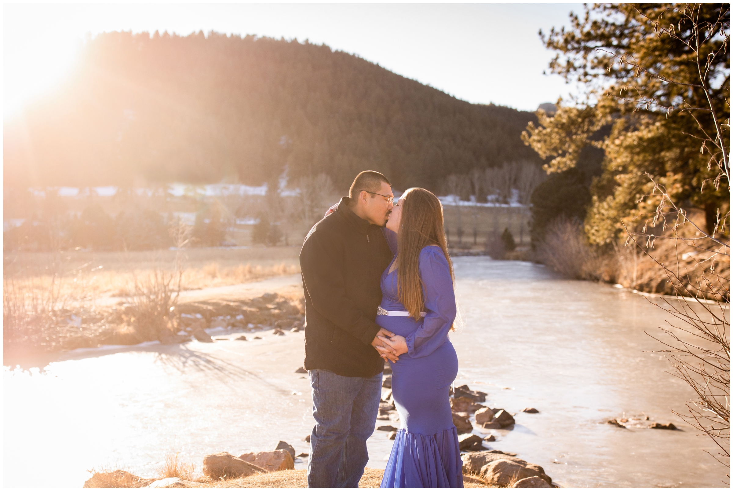 couple kissing in front of mountain lake during Evergreen Lake maternity photography session 