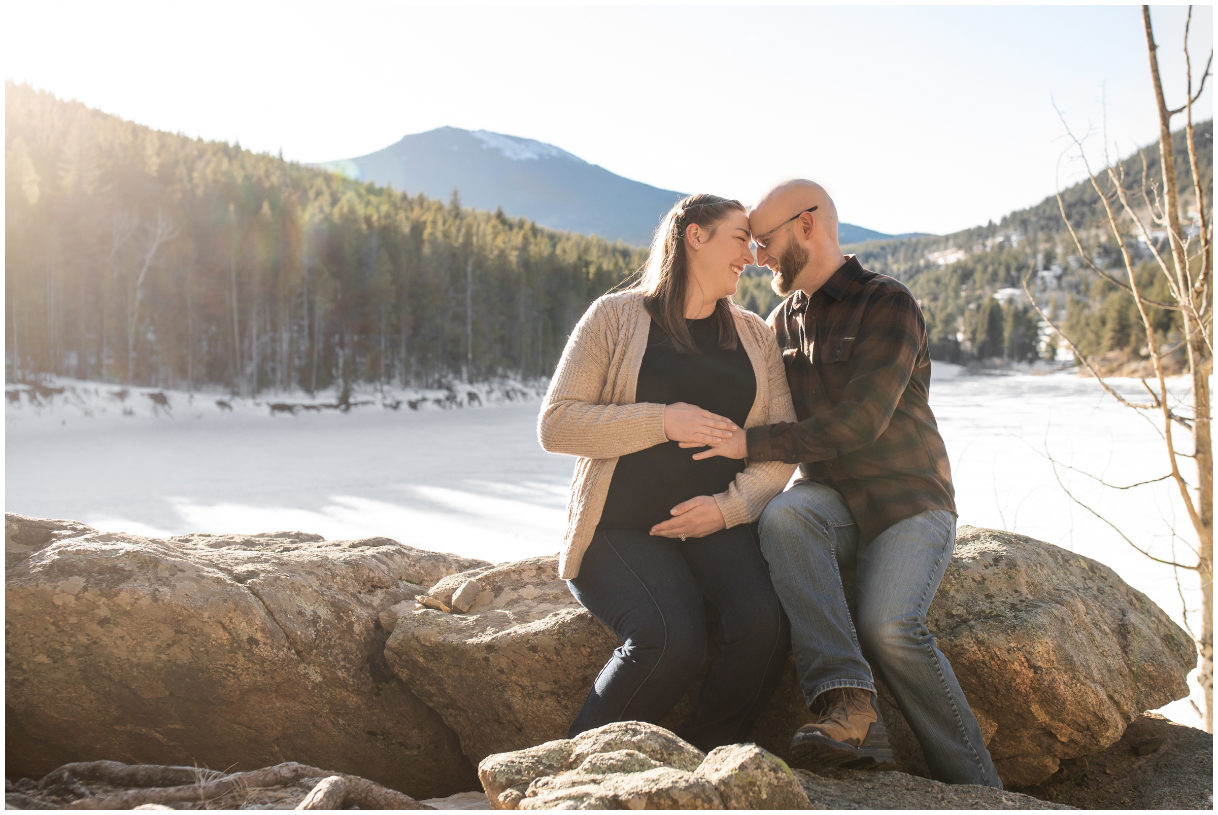 couple cuddling on rock formations during mountain maternity pictures at Beaver Brook Watershed Colorado 