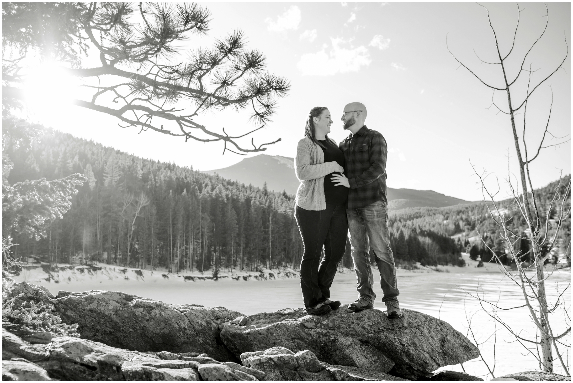 couple posing on rock formations during winter mountain maternity pictures in evergreen Colorado 