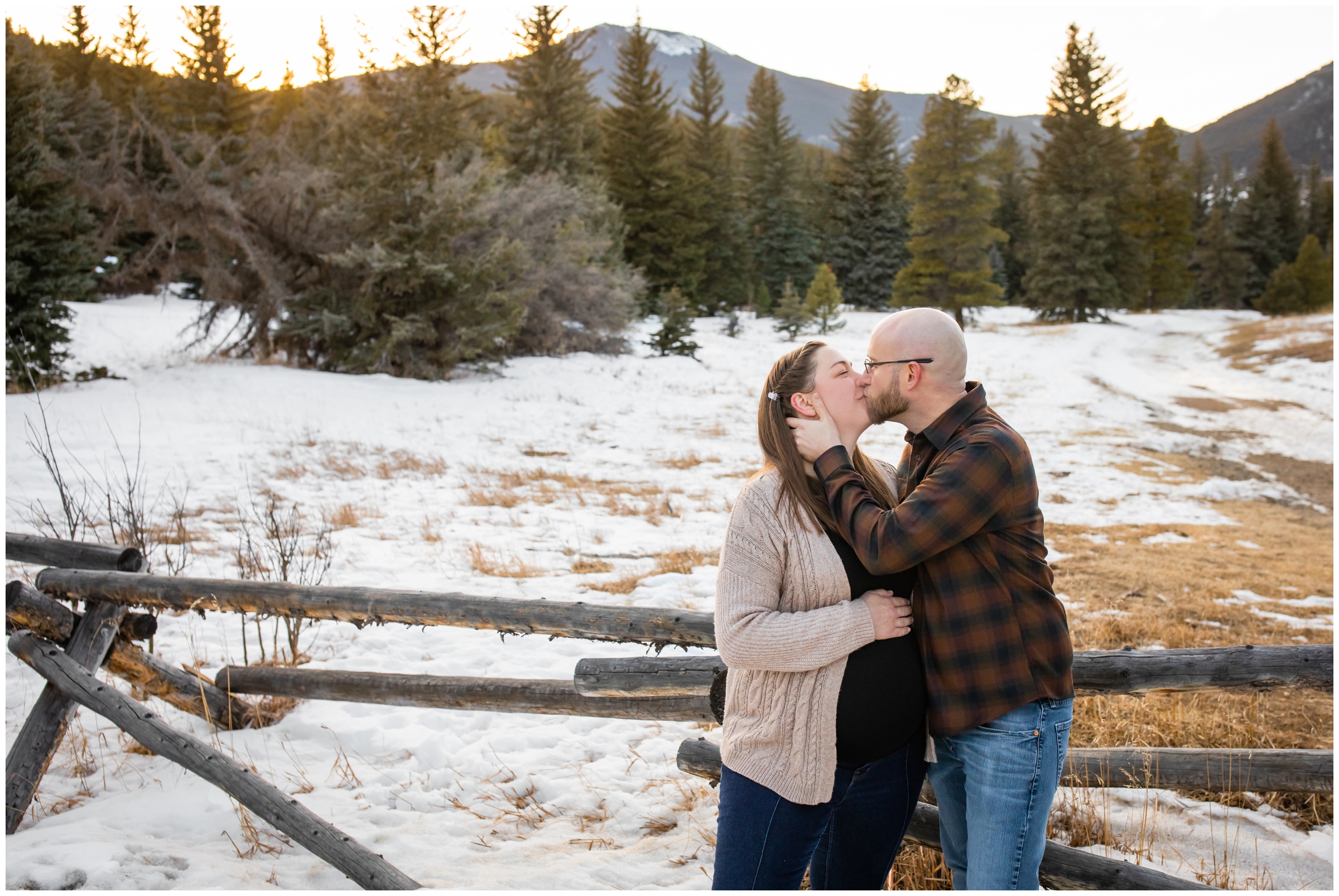 couple kissing in the snow during Evergreen Colorado mountain maternity pictures at Frosberg Park 
