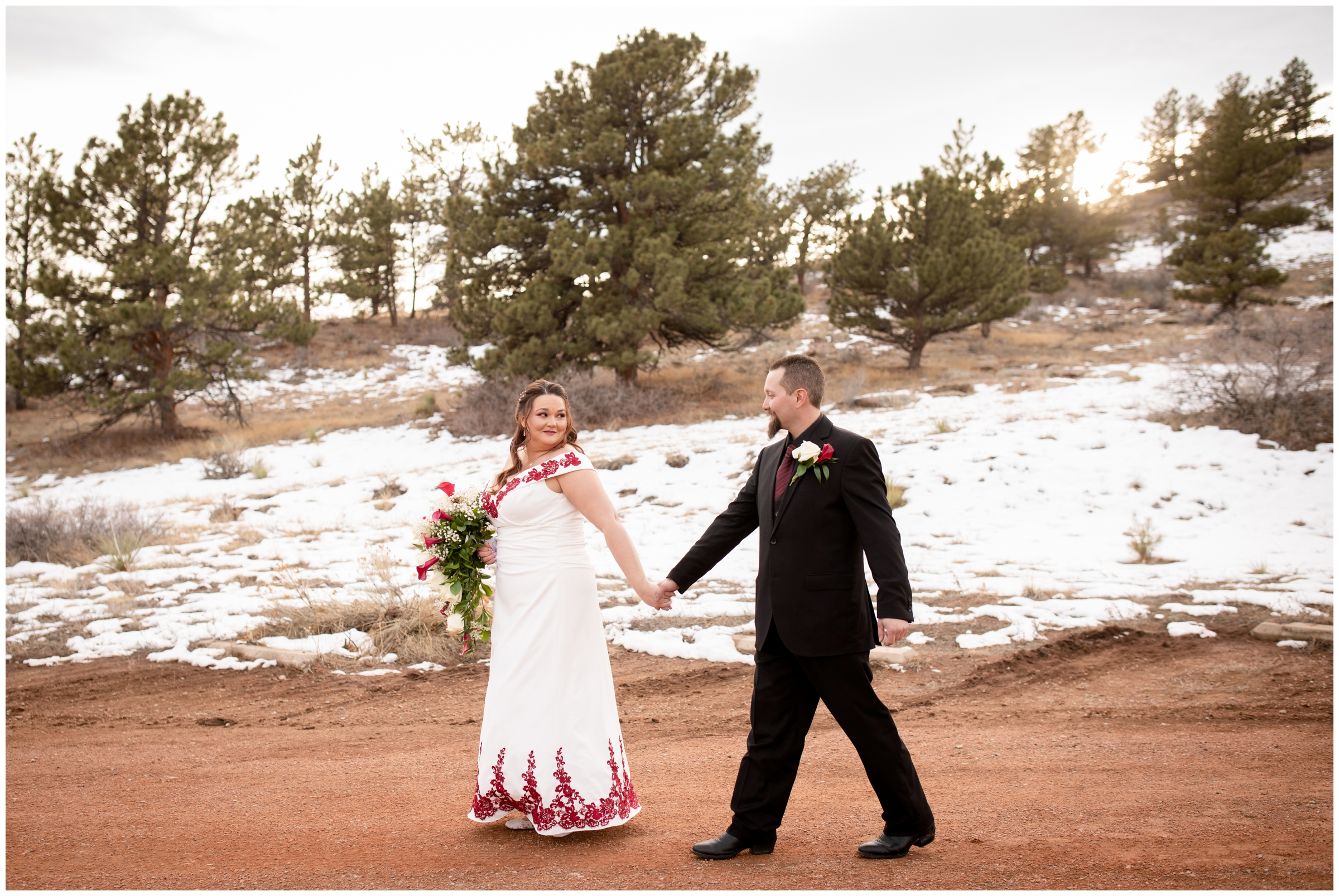couple walking down dirt road during Colorado winter wedding pictures in the snow