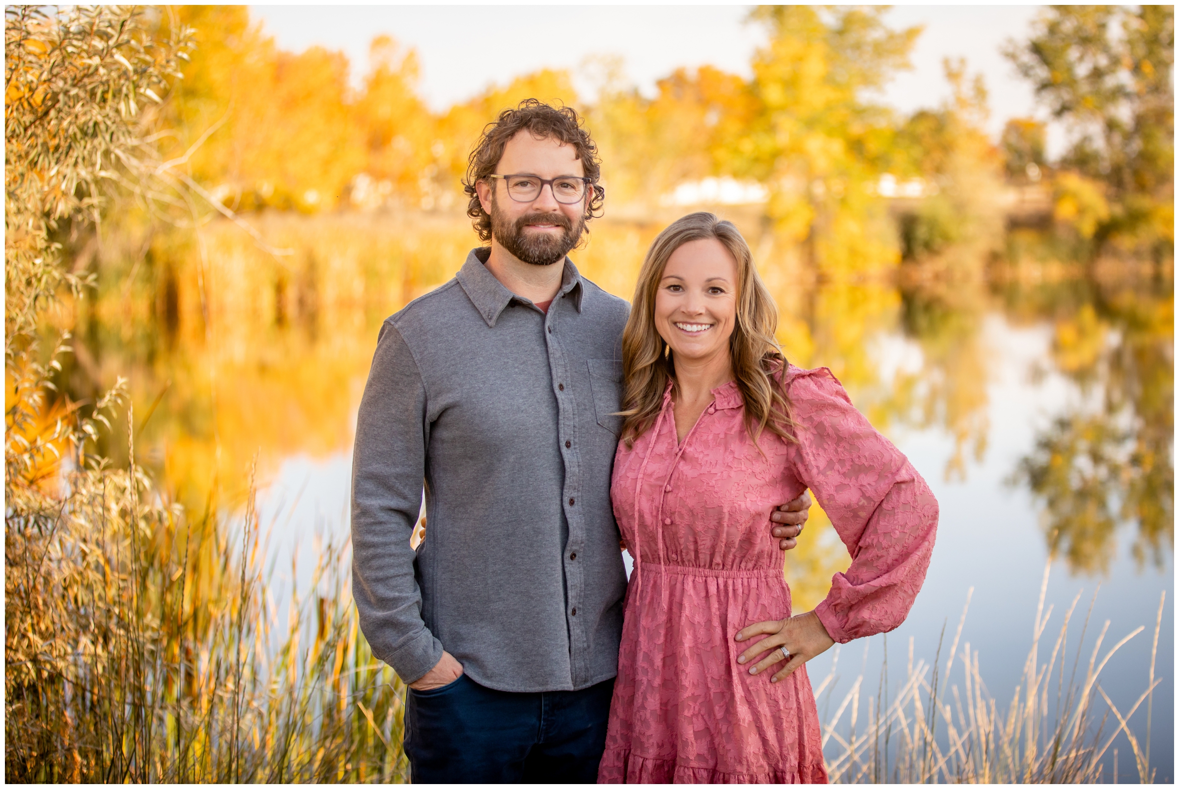 couple posing in front of colorful Colorado lake during fall at Idaho Creek Park Longmont 