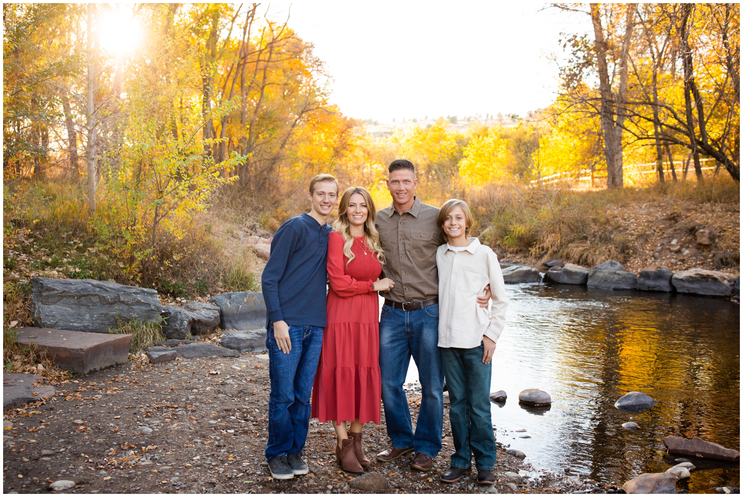 family standing by the river with colorful foliage  in background during Lyons Colorado fall family photos at Bohn Park