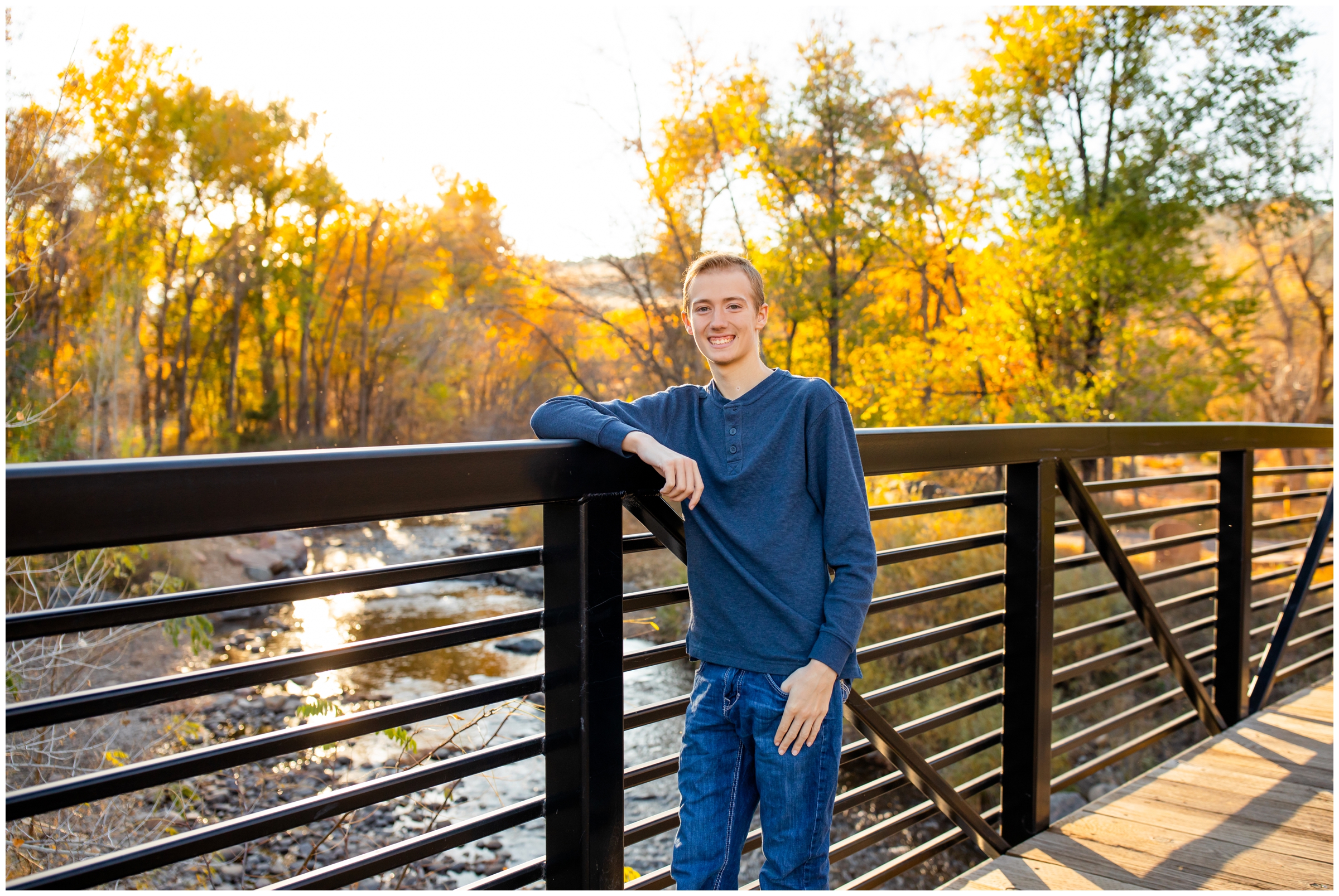 young man leaning against bridge during college graduation portraits in the Colorado mountains