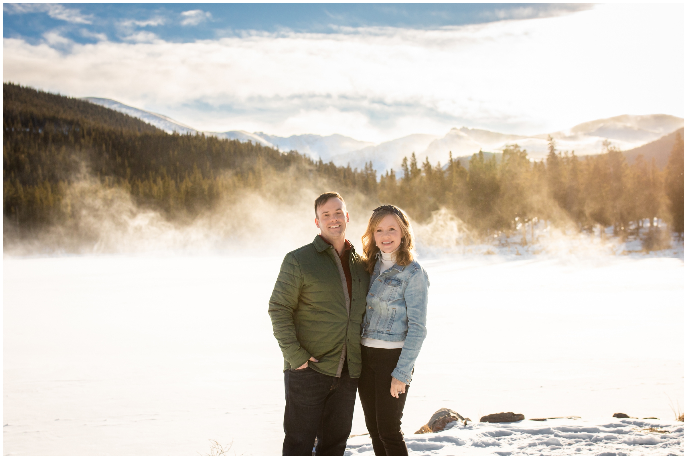 couple posing in front of snowy mountain backdrop during winter engagement couples at Echo Lake in Idaho Springs Colorado