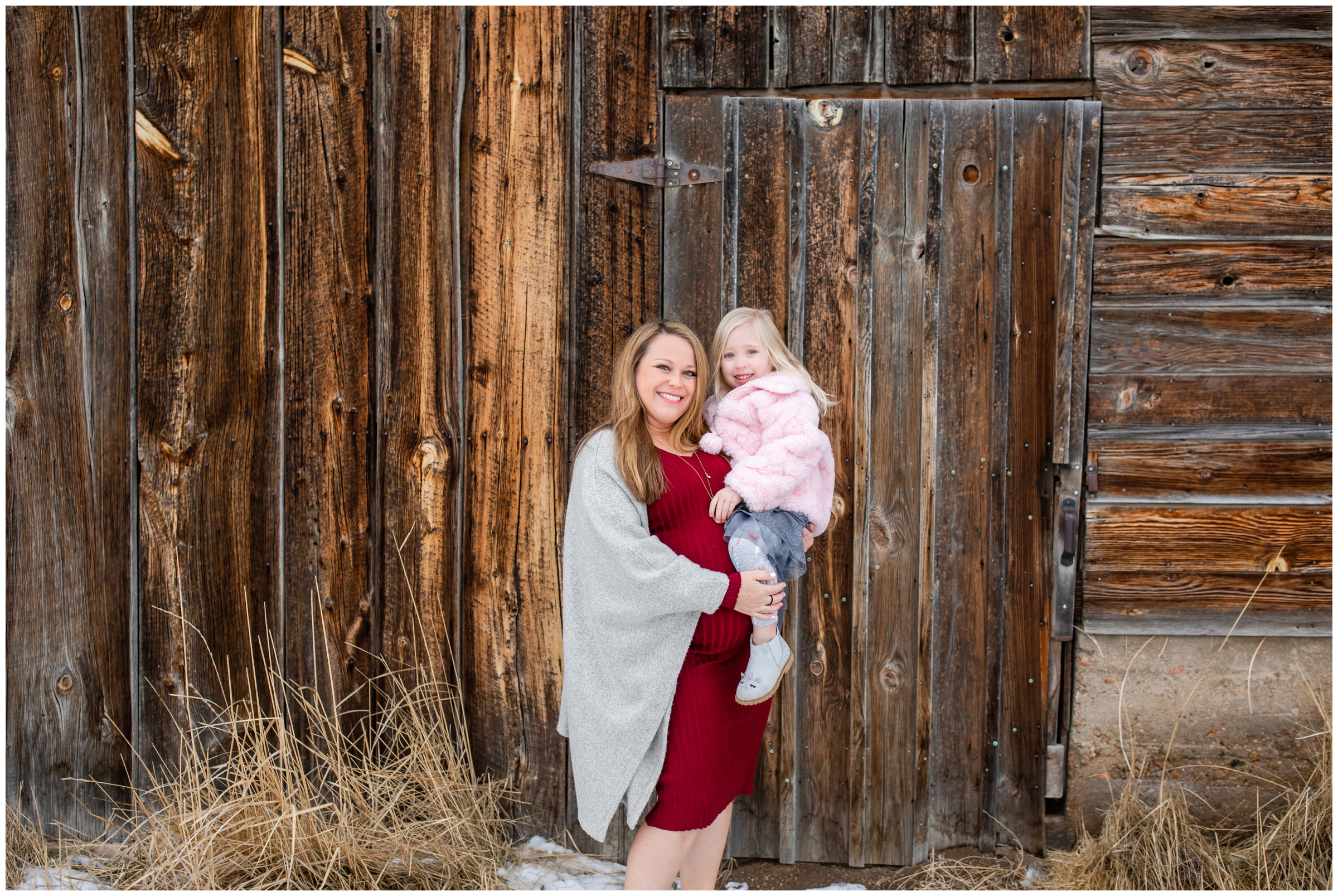 pregnant mom holding her daughter during Longmont winter family photos at the barn at Sandstone Ranch 