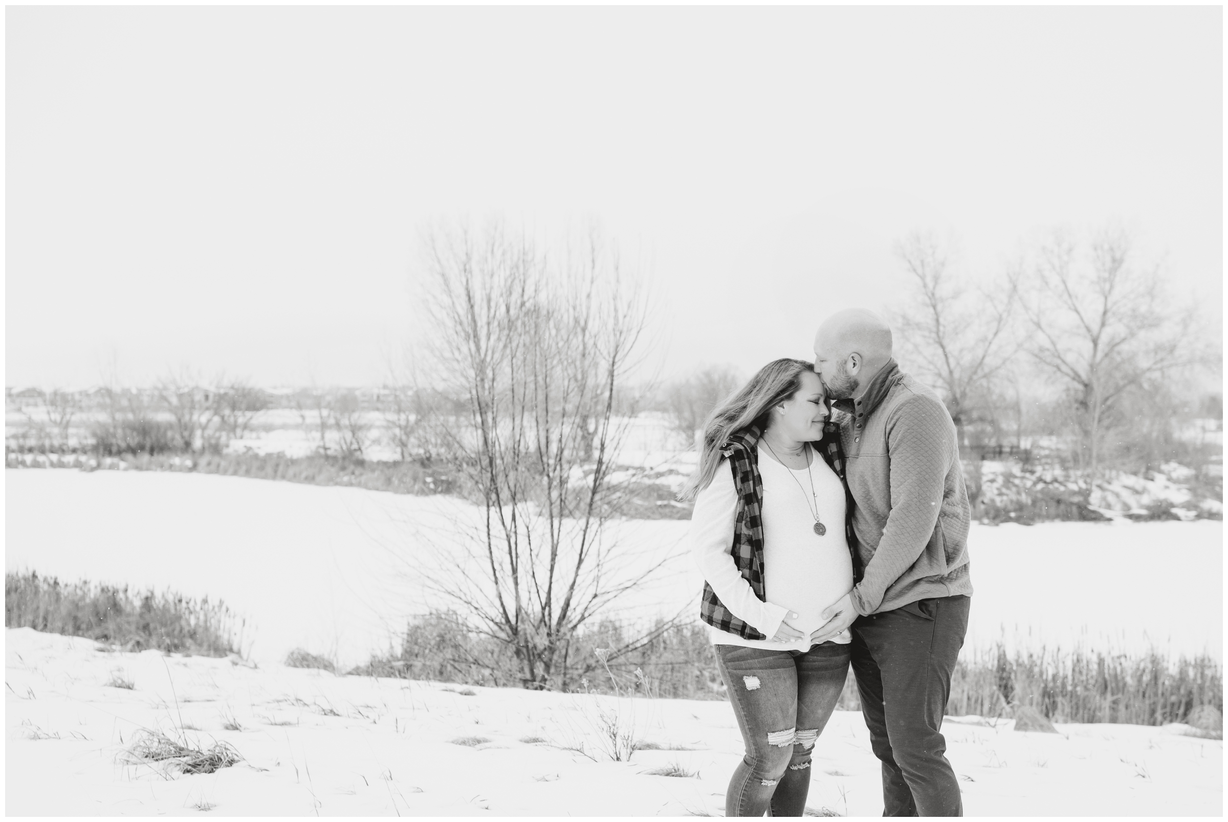 couple kissing in the snow during winter maternity pictures at Sandstone Ranch in Longmont Colorado