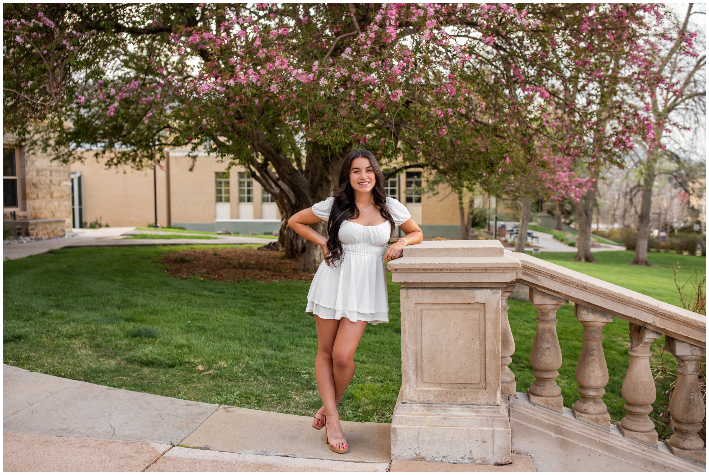 woman posing against cherry blossoms during spring college senior pictures in Colorado 