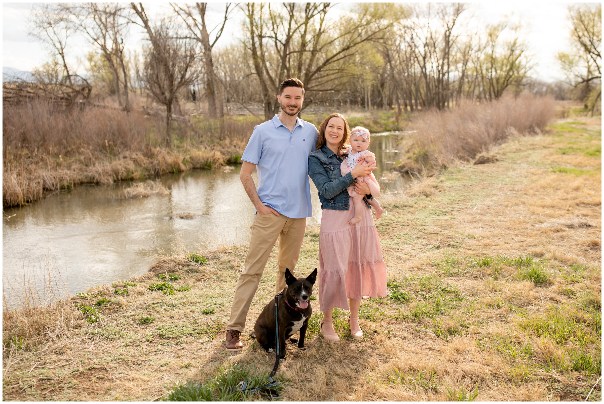 couple posing by the river with their dog during Longmont family portrait photography session at Sandstone Ranch 