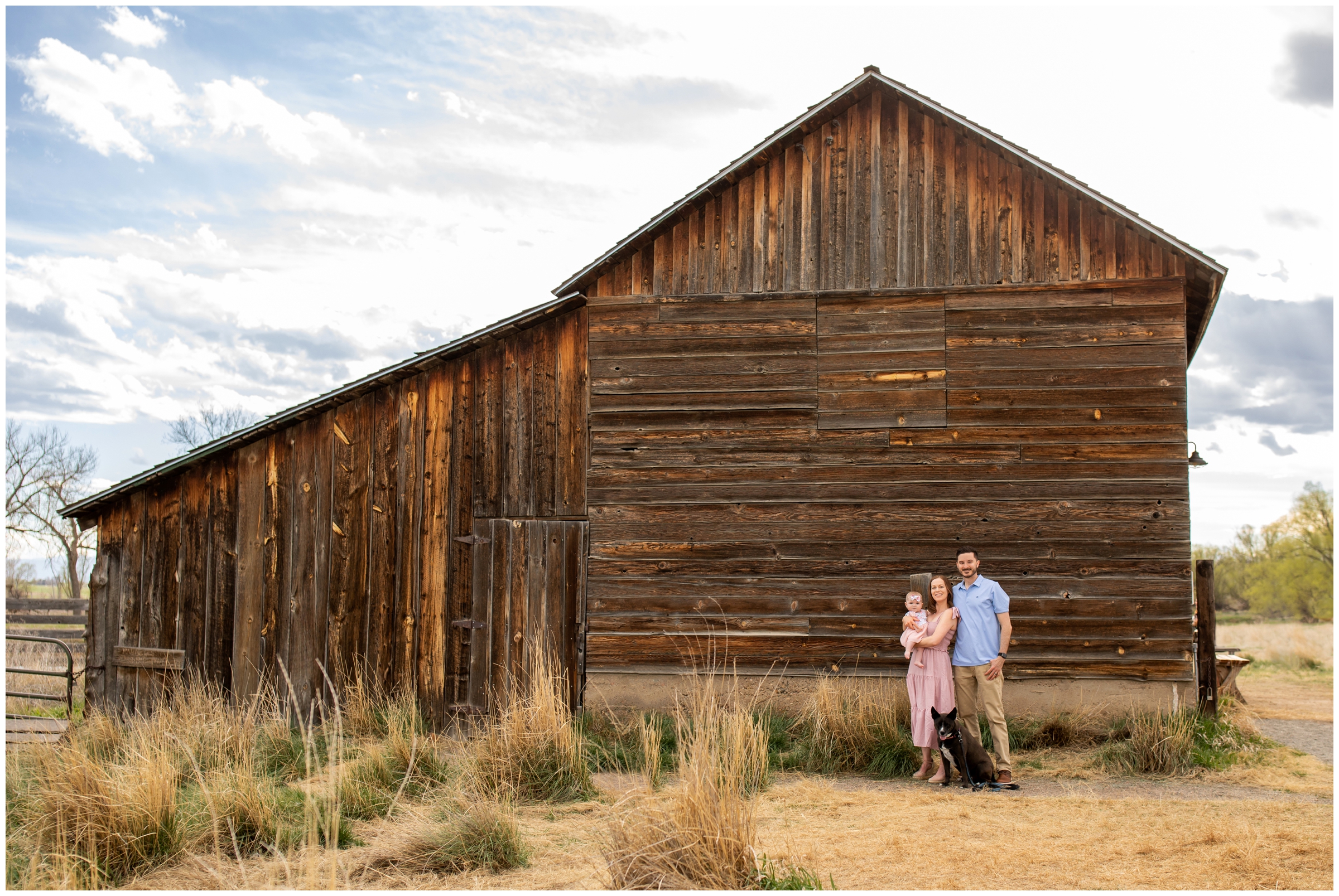 family posing in front of wooden barn at Sandstone Ranch Colorado