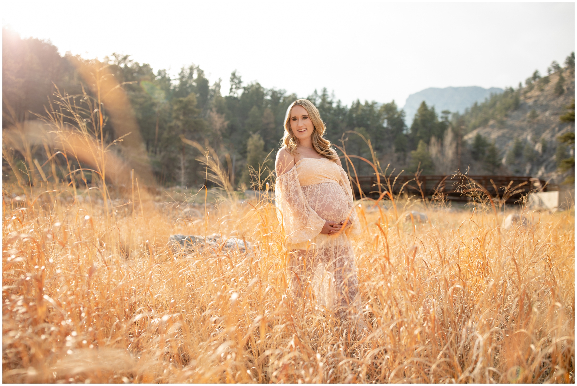 pregnant woman posing in field of long grasses during spring maternity photos in Loveland Colorado 