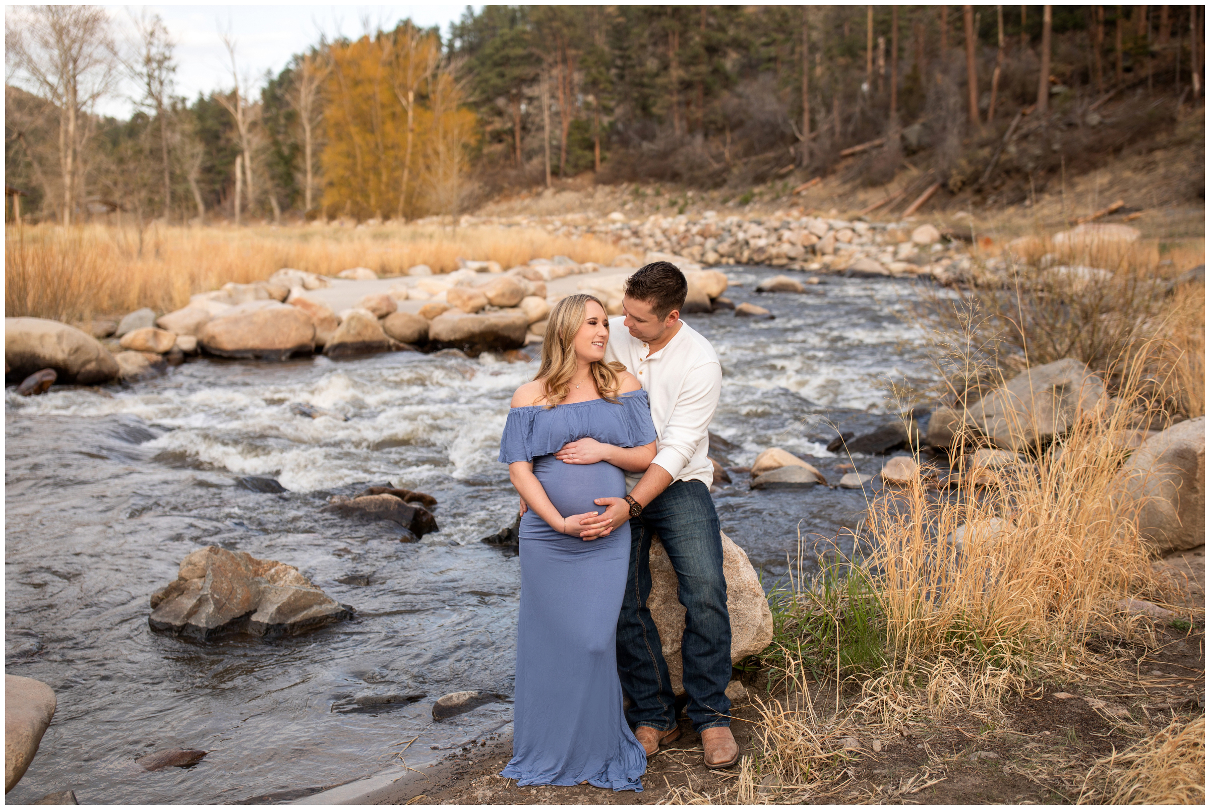 couple sitting on big rock along the river during Loveland Colorado maternity portraits by Plum Pretty Photos