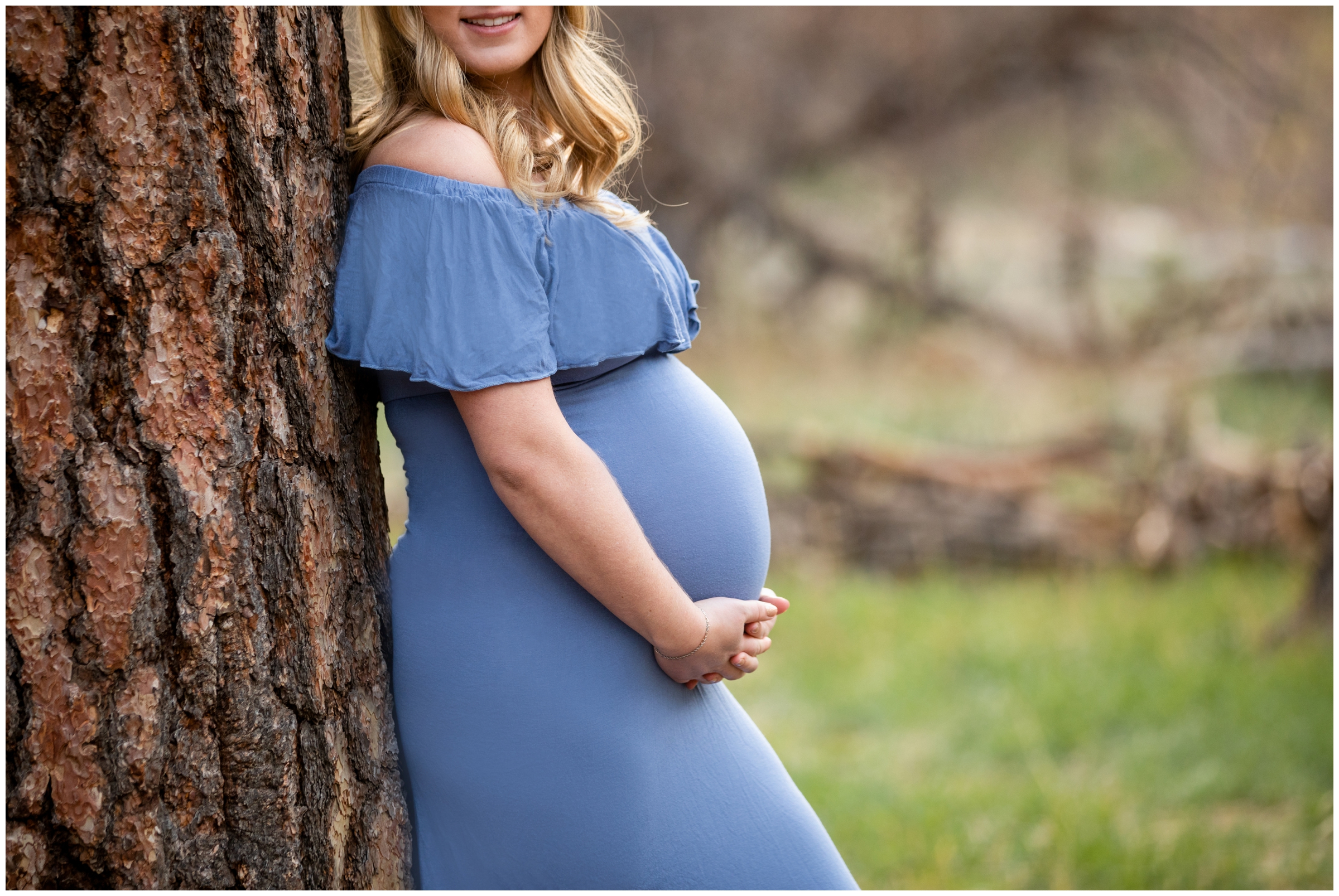pregnant woman leaning against tree in periwinkle off-the-shoulder maternity dress