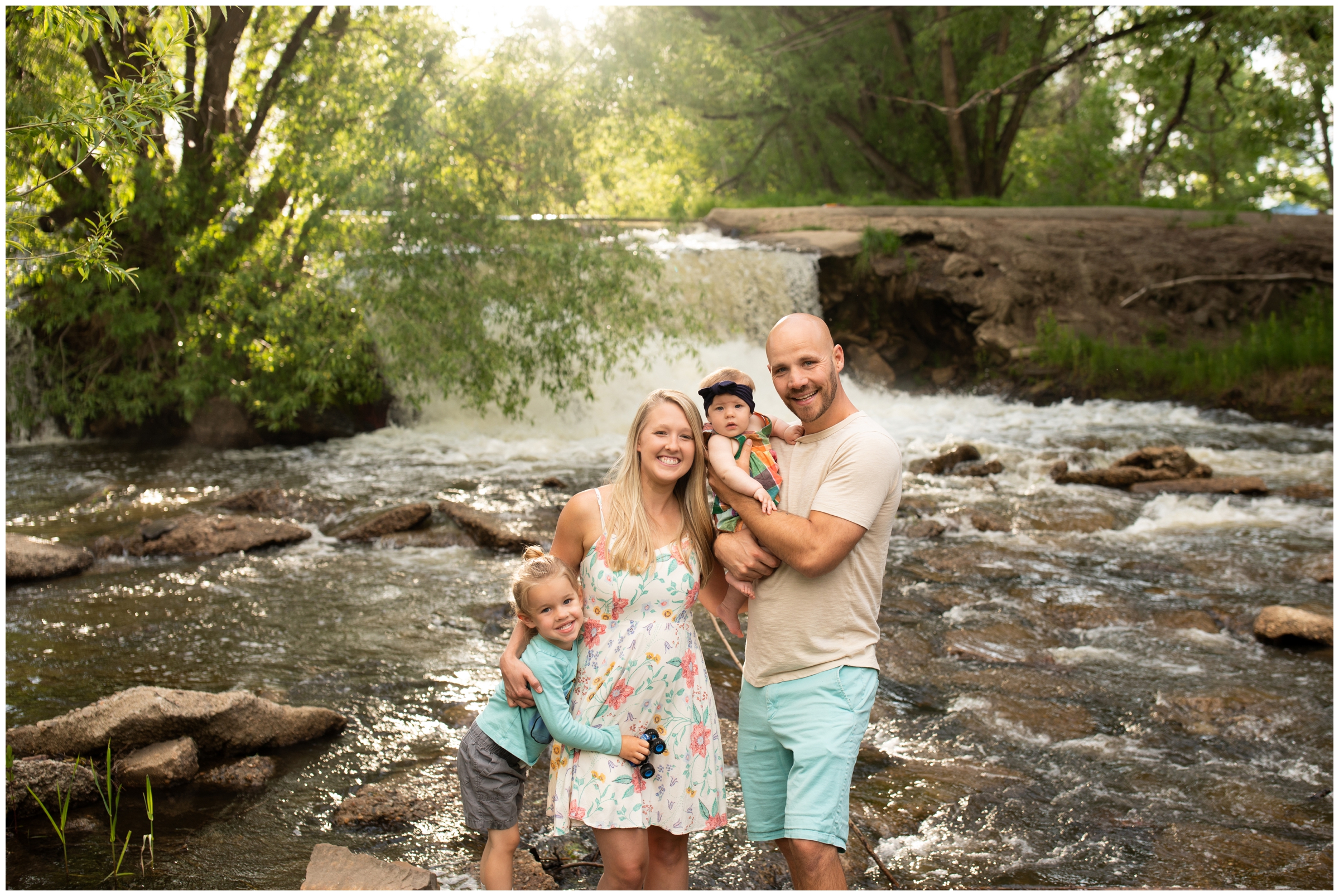family posing next to waterfall during family photography session at Golden Ponds in Longmont Colorado 