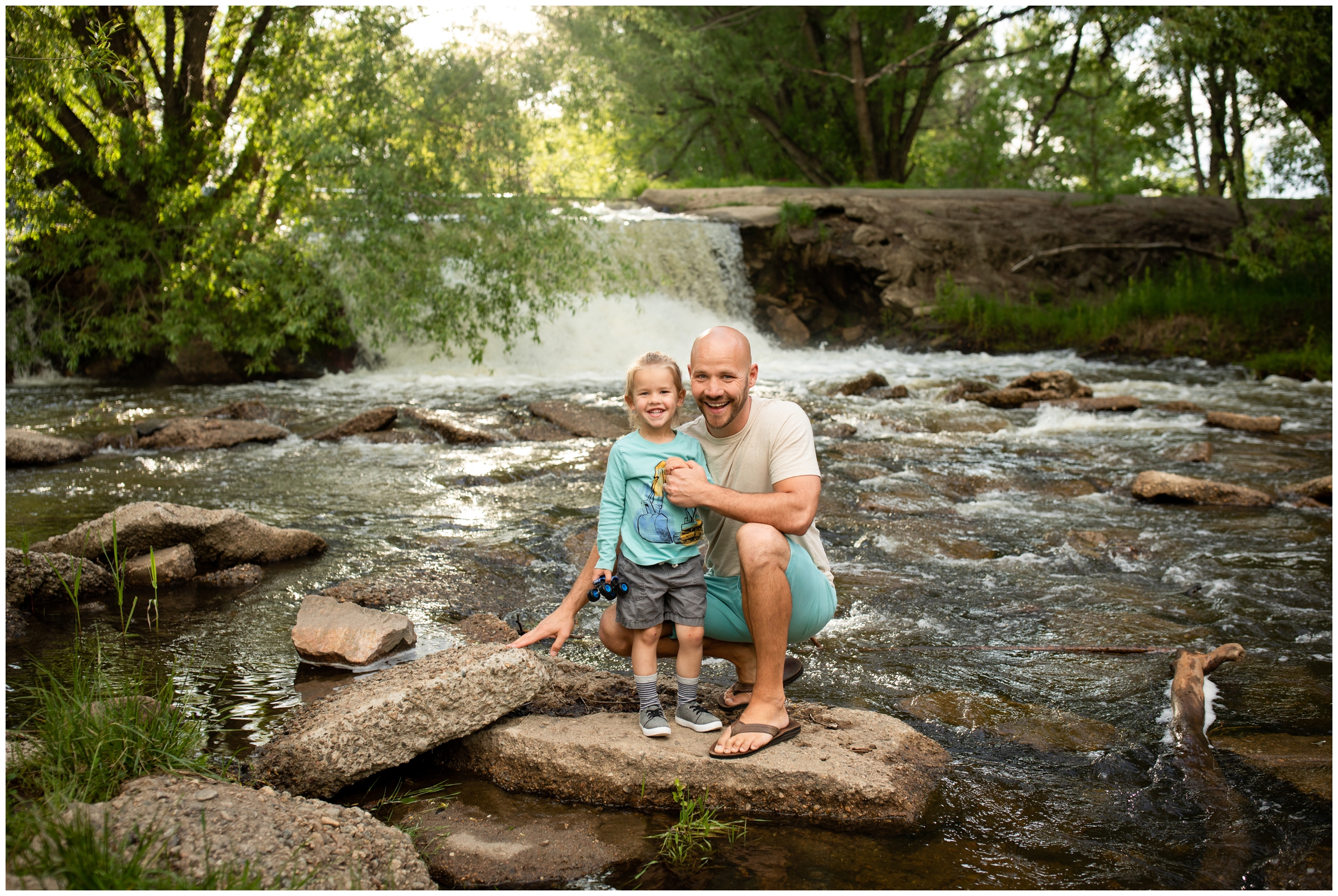 dad and son posing by waterfall at Golden Ponds in Northern Colorado 