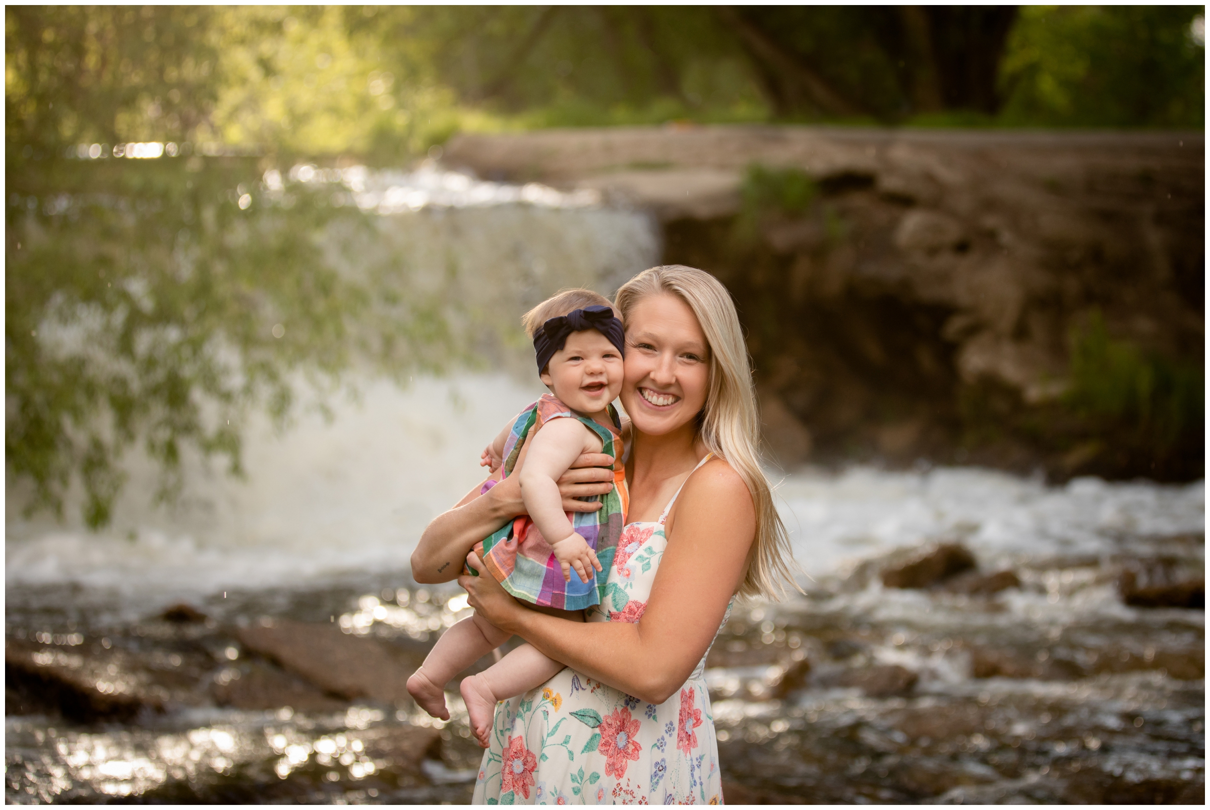 mom holding baby daughter with waterfall in background during Longmont Colorado family pictures 