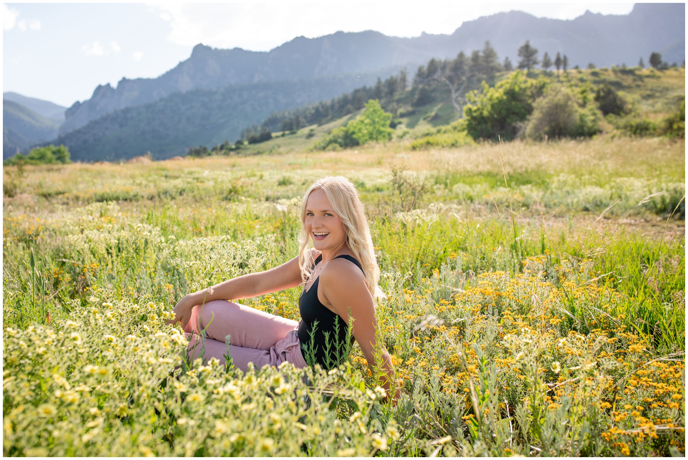 teen sitting in a field of flowers during mountain graduation senior pictures in Boulder 