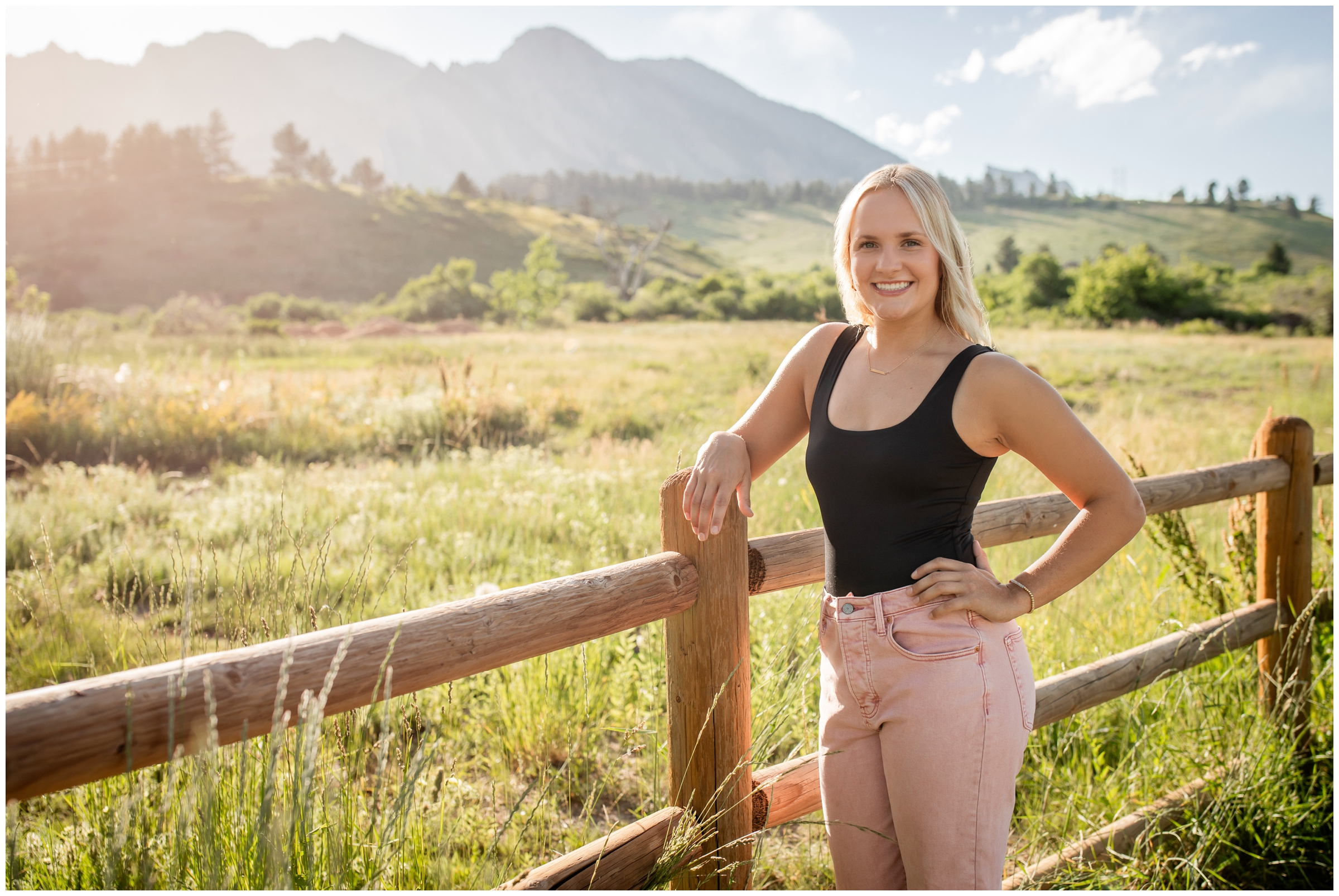 teen leaning against a fence during Boulder flatirons senior photography session in Colorado