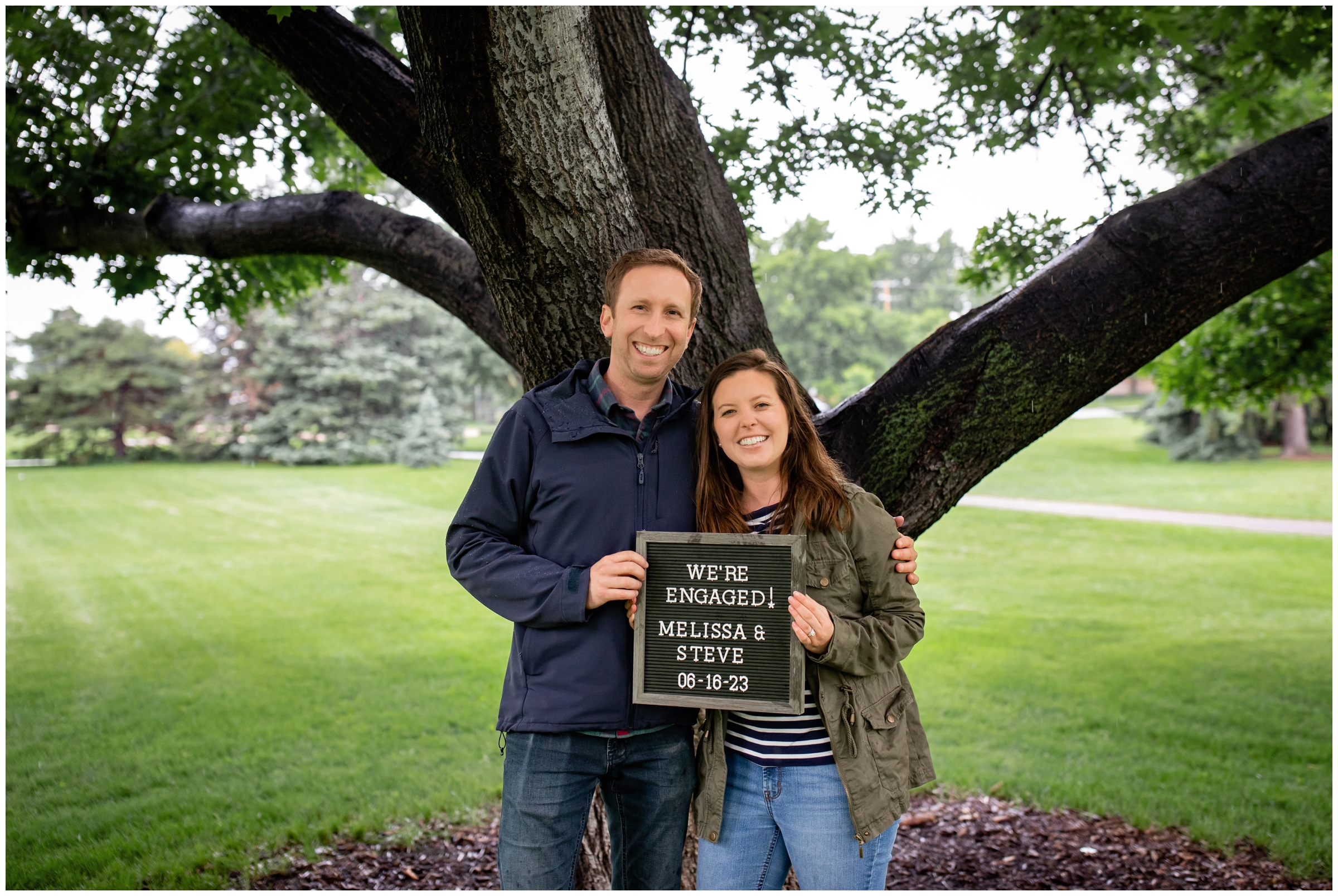 couple holding custom sign after surprise proposal in a Denver park 