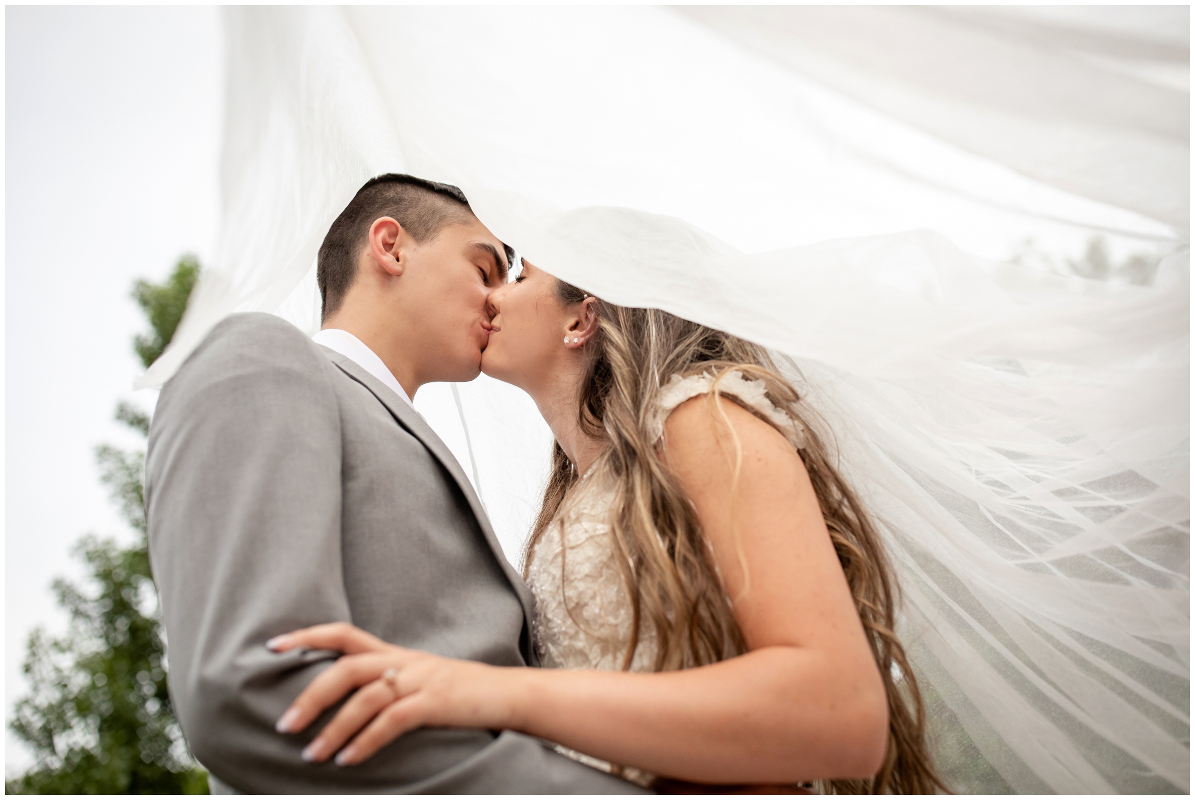 couple kissing under bride's veil during romantic wedding portraits at River Bend in Lyons Colorado 