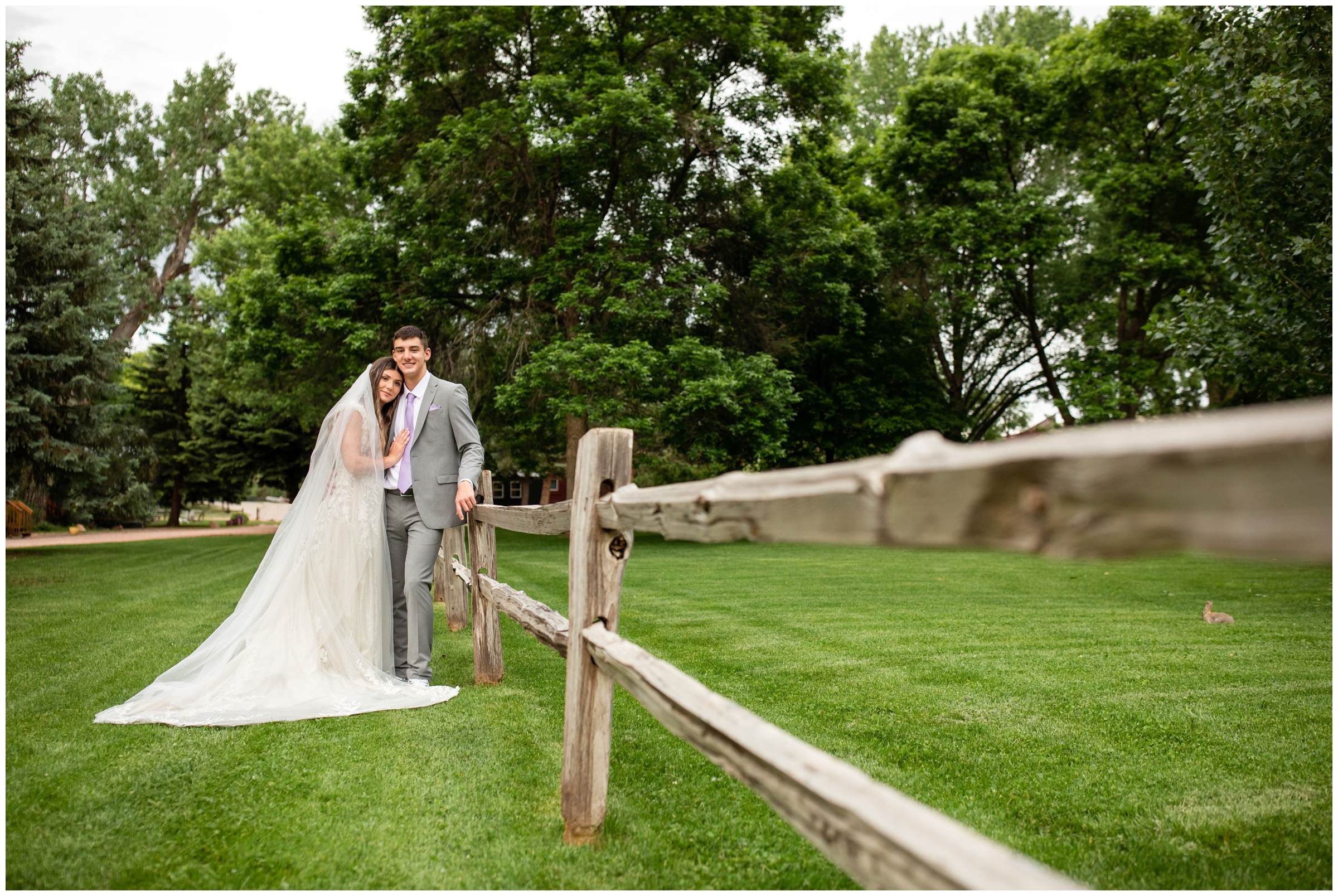 couple leaning against wooden fence during Lyons Farmette River Bend summer elopement wedding portraits 