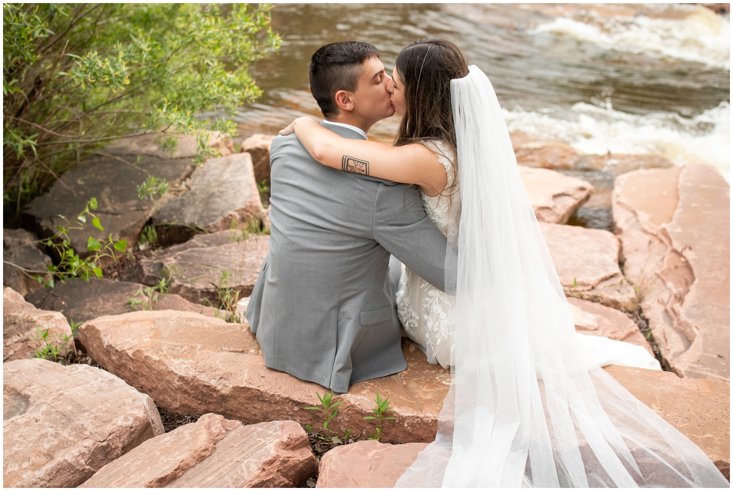 couple kissing next to the river during Lyons farmette elopement wedding photos by Plum Pretty Photography 