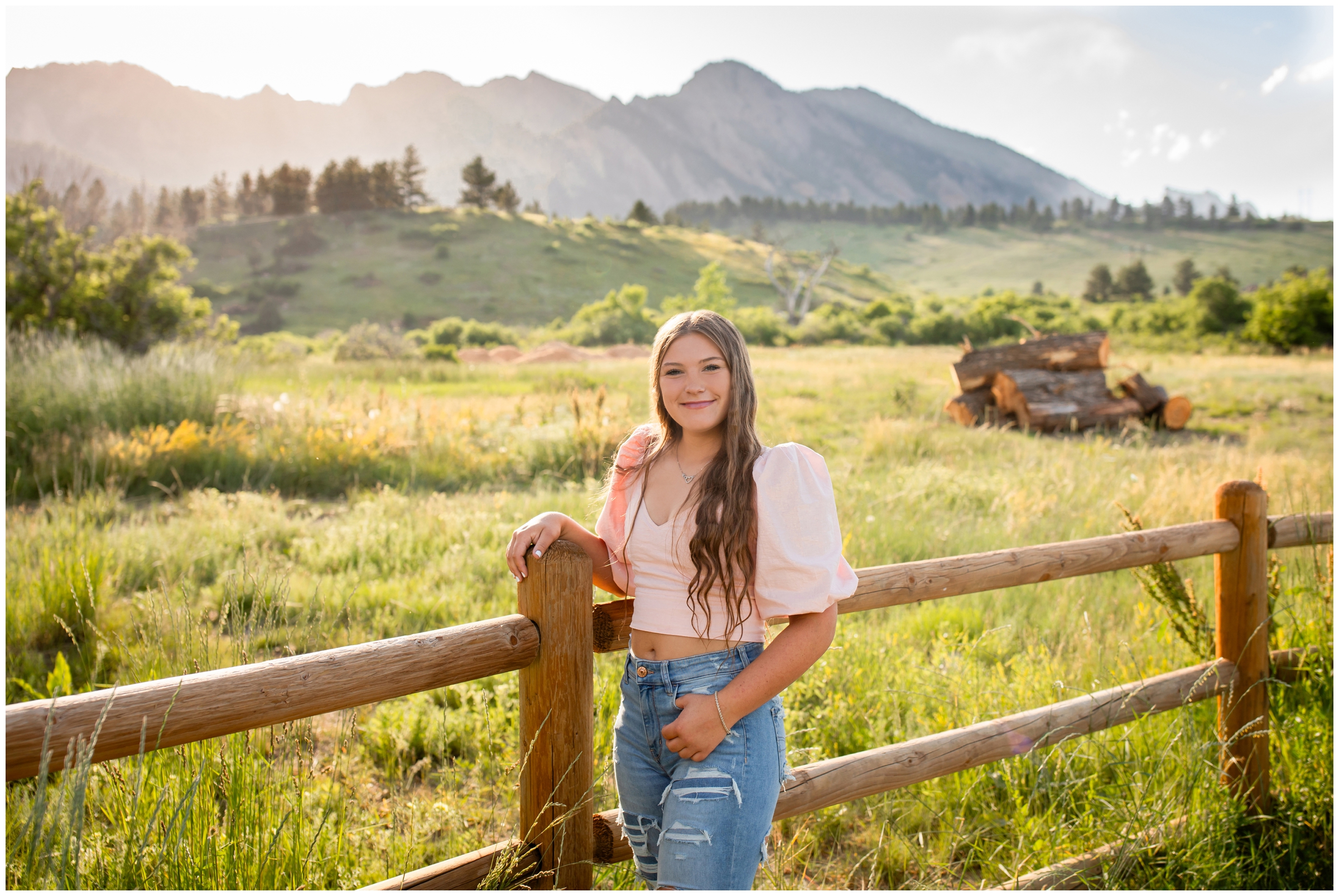 teen leaning against fence with flatirons mountains in background during Boulder senior portraits by Plum Pretty Photography 